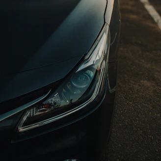 Close-up of a dark car headlight at sunset