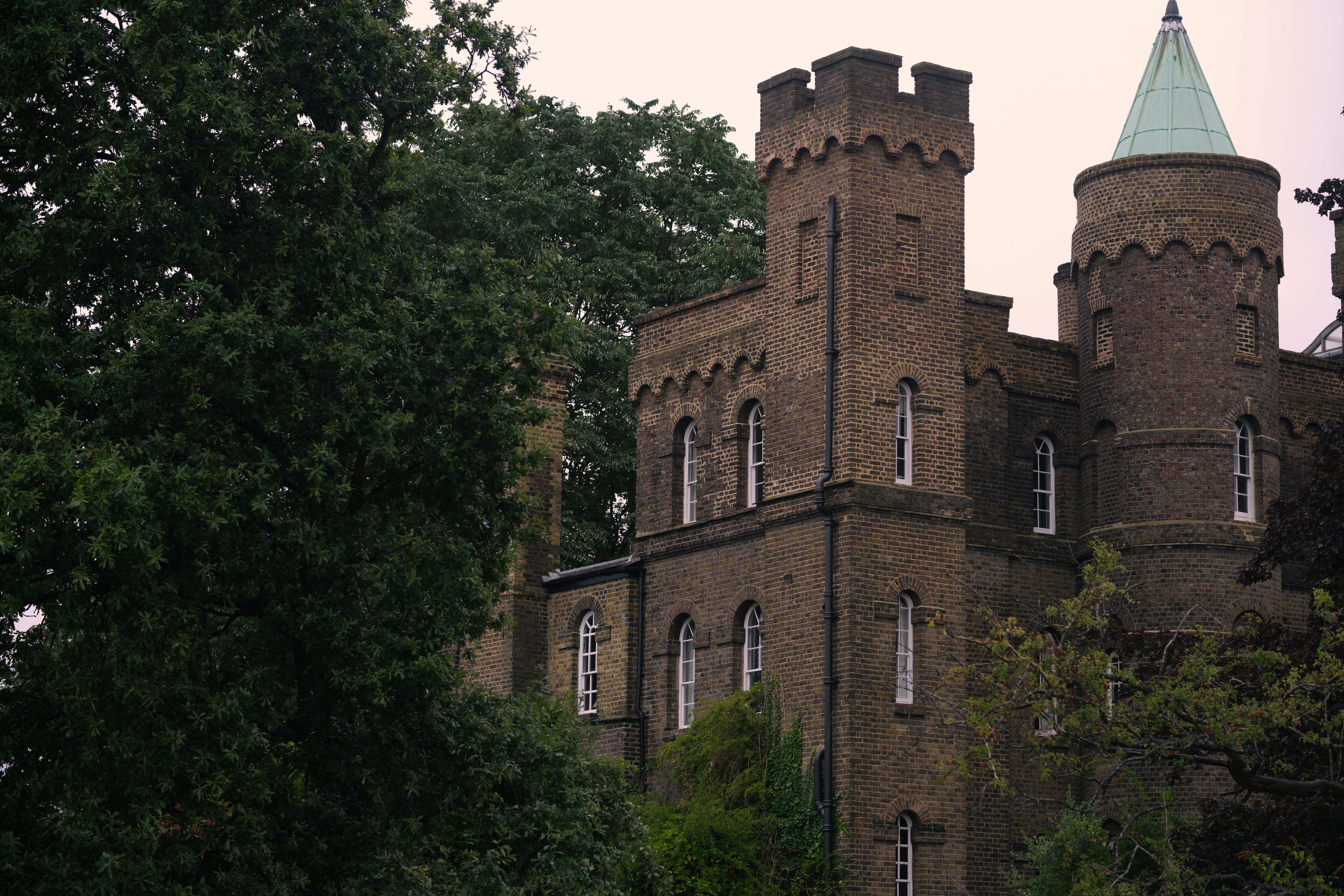 Backsteinburg mit grünem konischem Dach und Bäumen