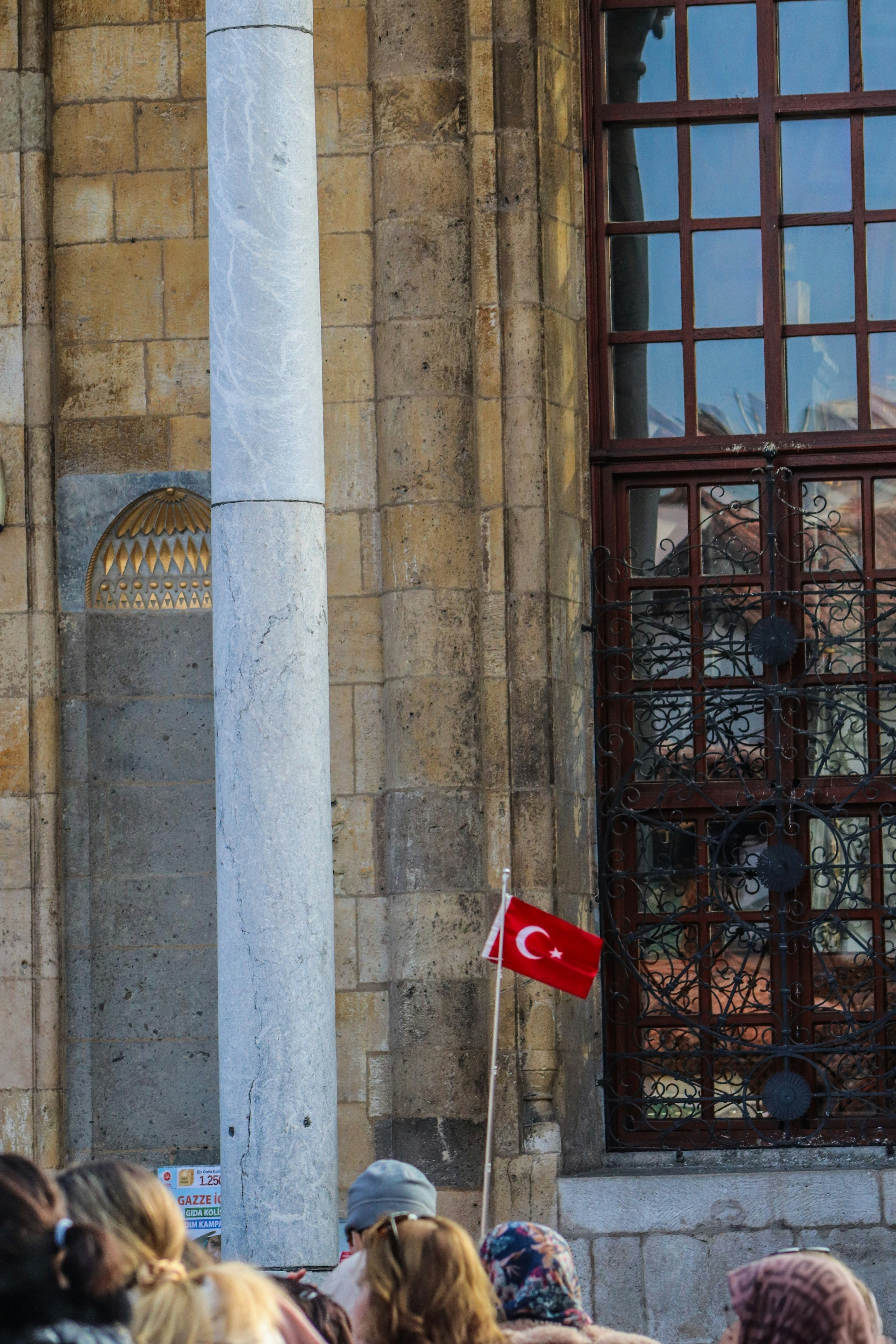 Turkish flag waving near a building with a large window