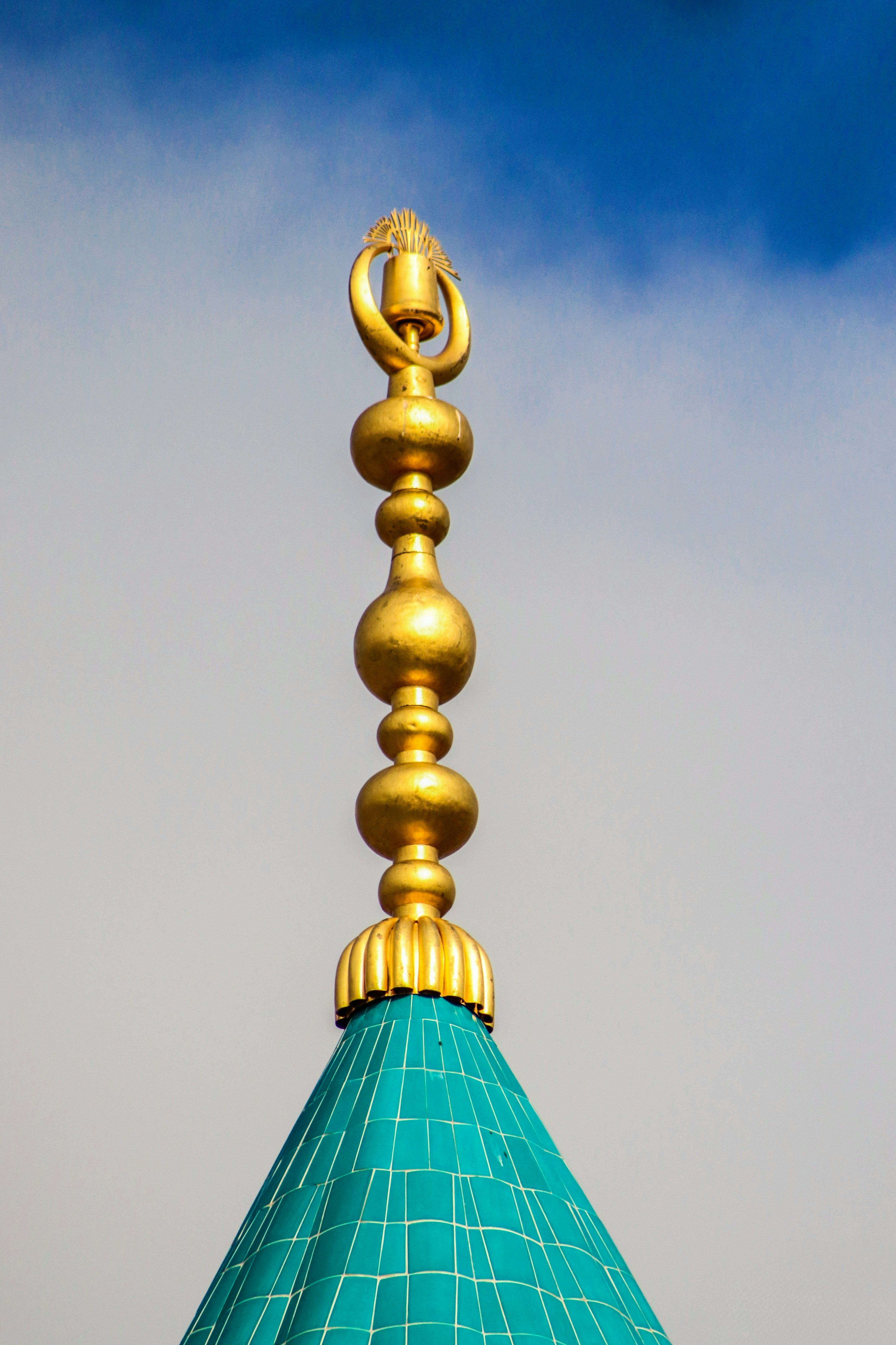 Golden finial atop a turquoise tiled dome.