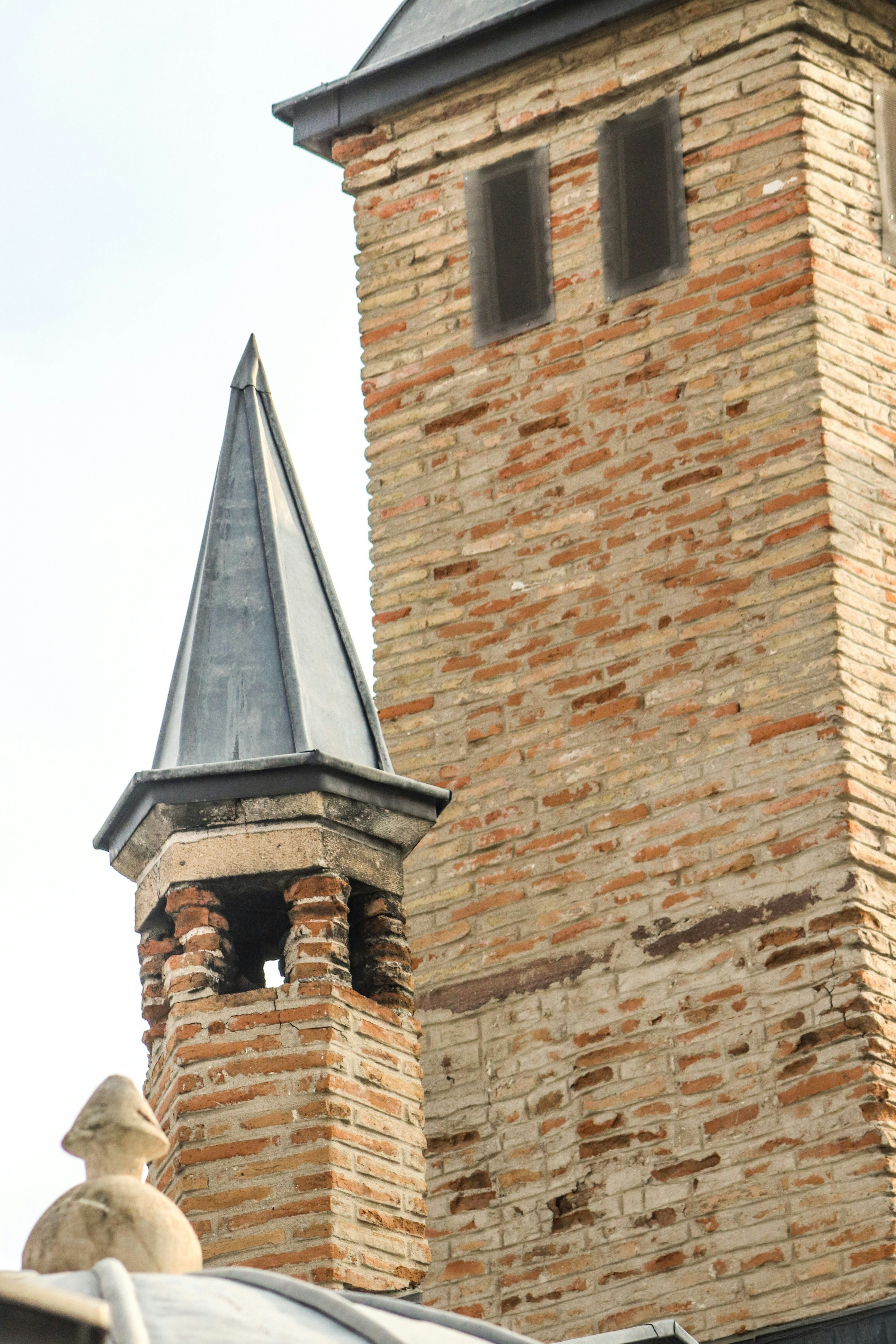 Close-up of a brick tower with a spire.