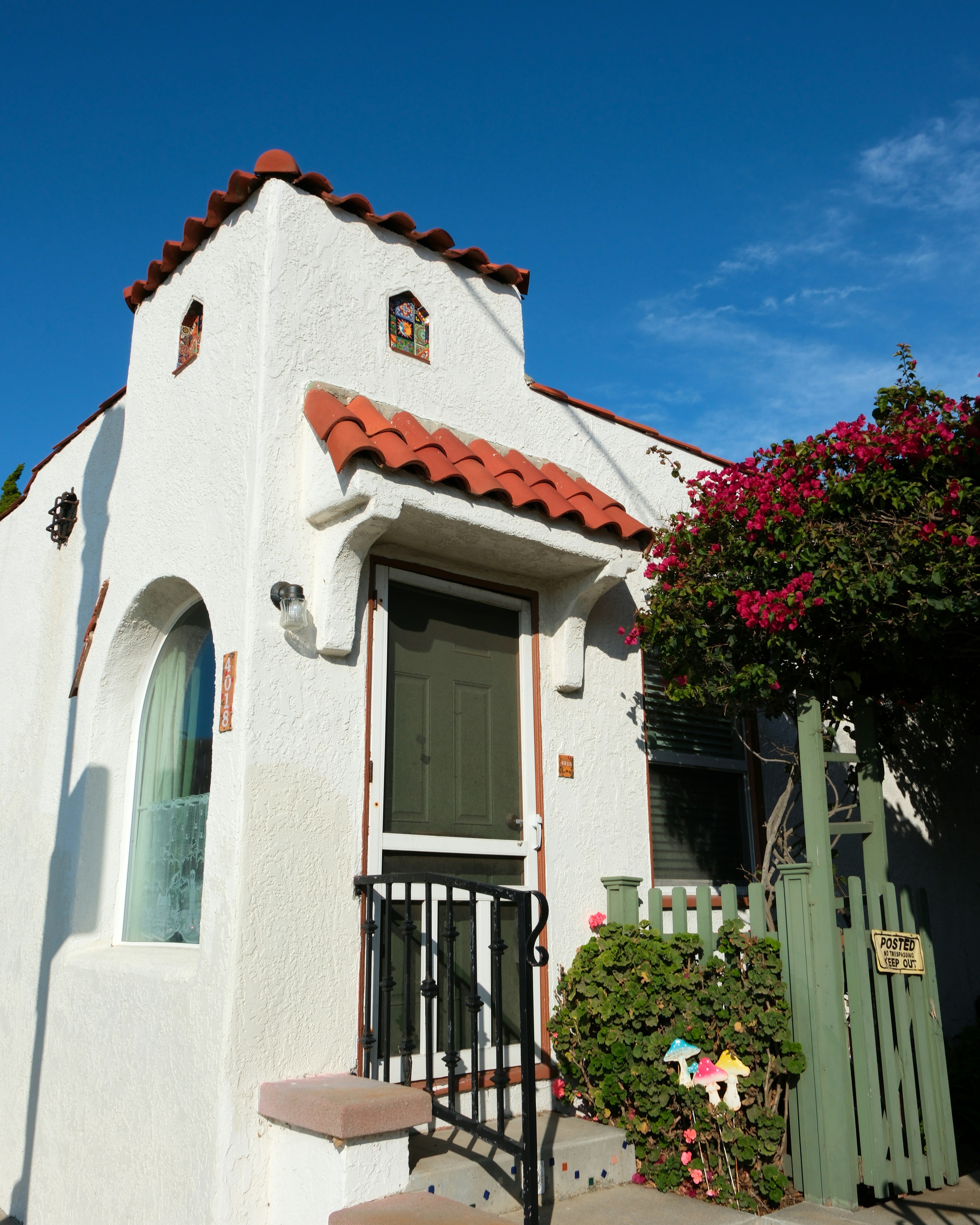 Casa in intonaco bianco con tetto in tegole rosse e bougainvillea.