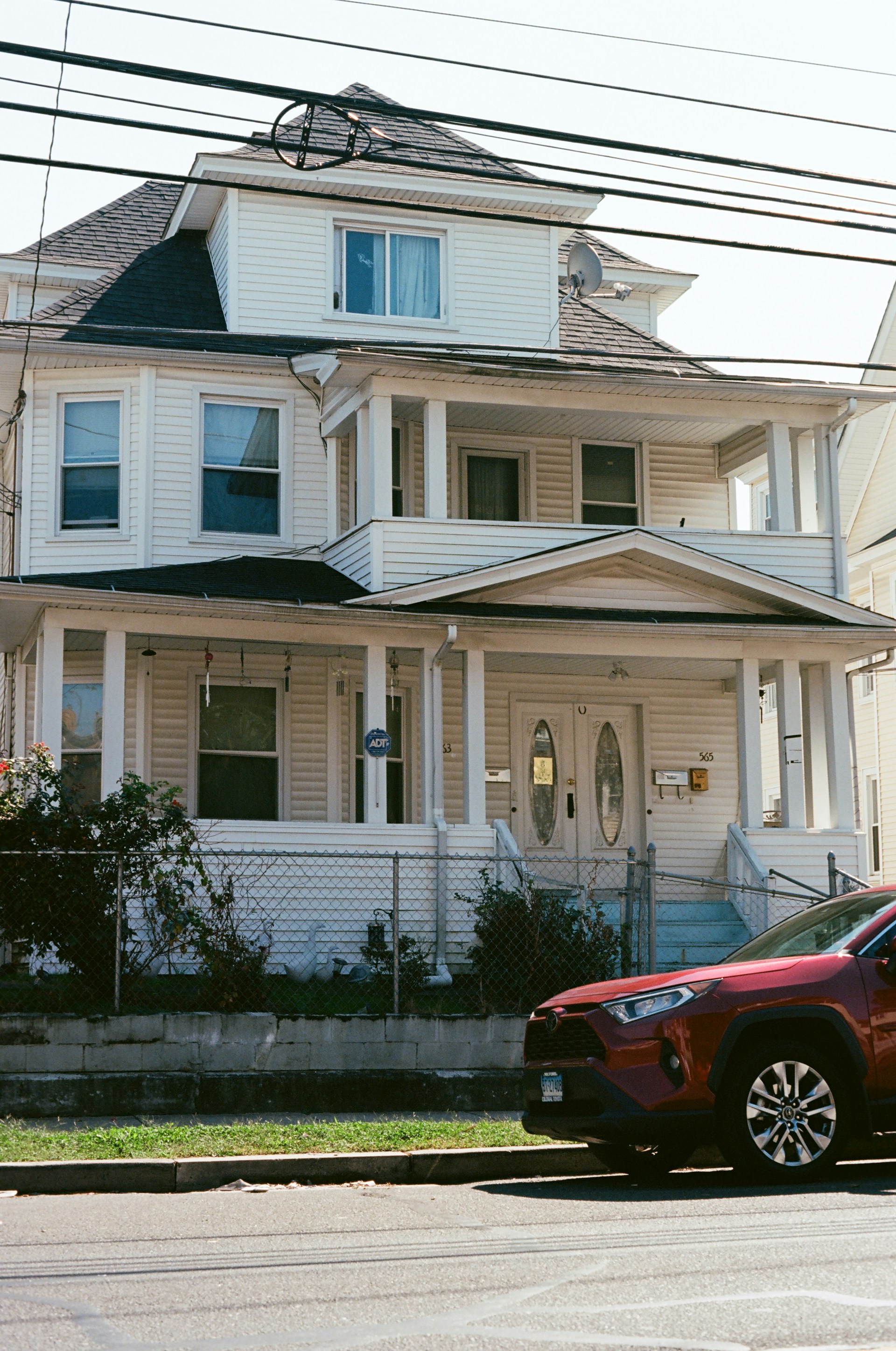 Cream-colored house with white trim and a red car.