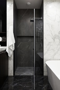 Modern bathroom with marble and dark stone shower.