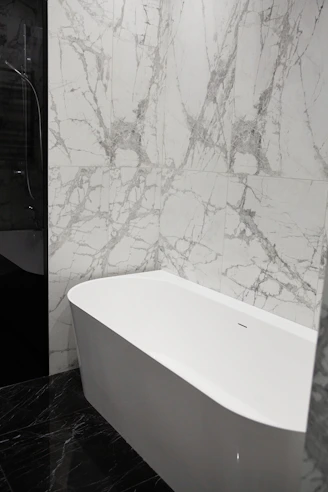 Modern bathroom with white bathtub and marble walls