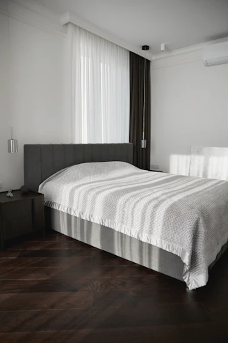 Modern bedroom with a large bed and dark wood floor.