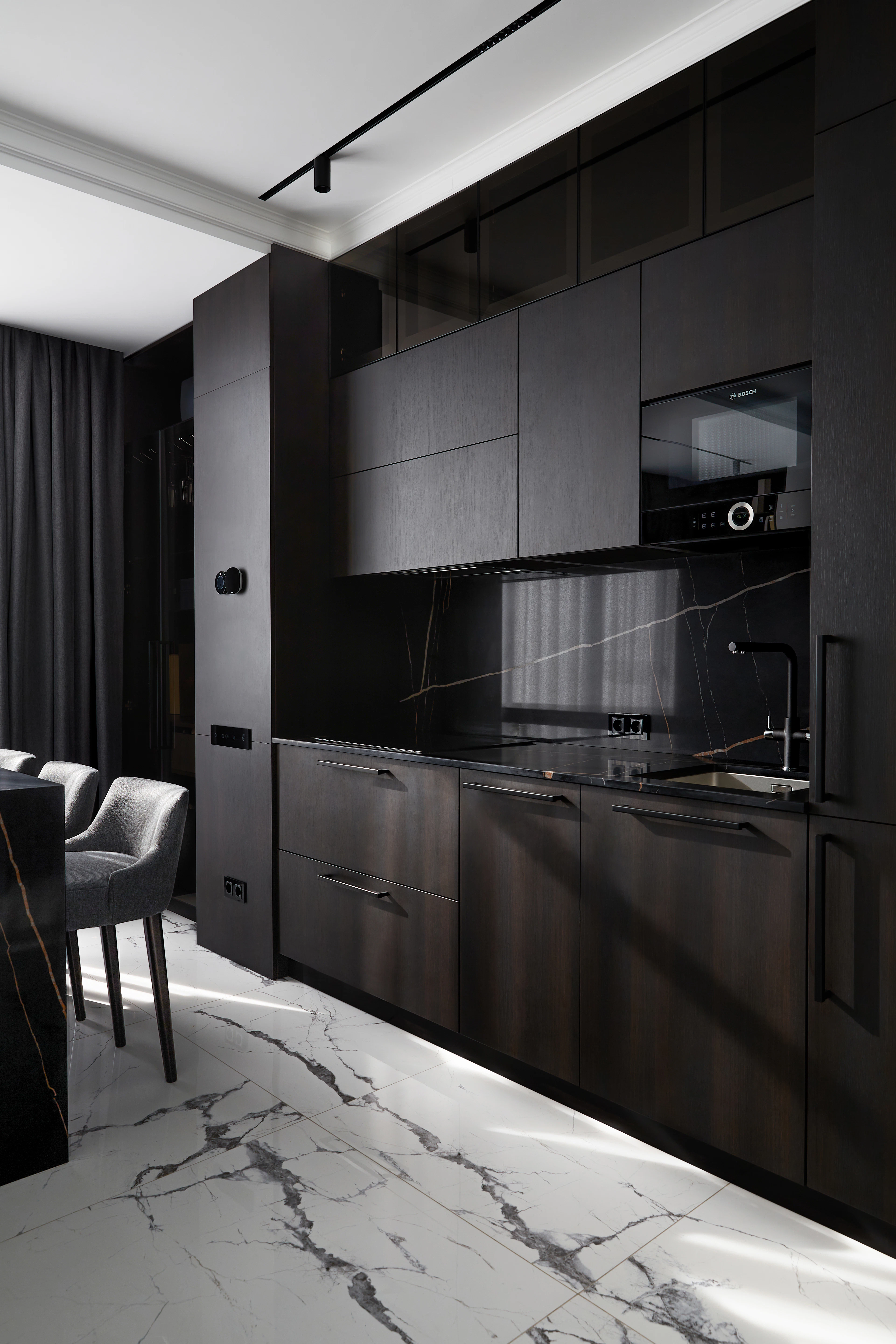 Bespoke dark kitchen with book-matched stone and integrated appliances