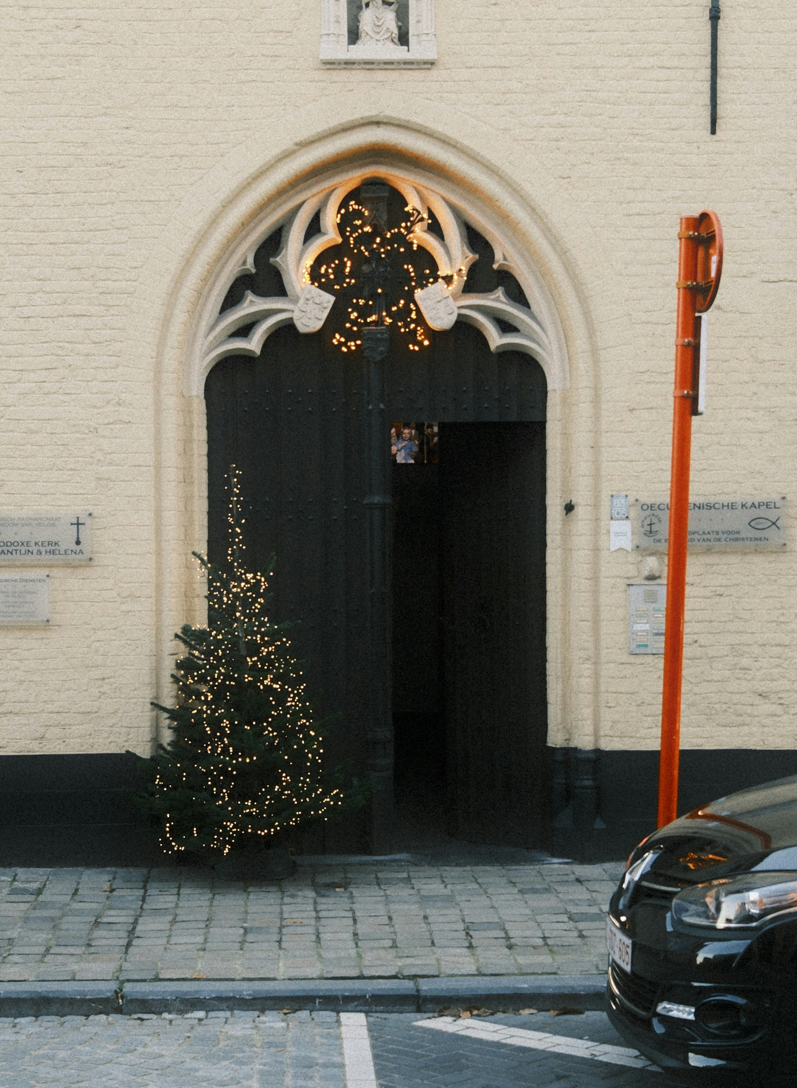 Decorated christmas tree outside a dark arched doorway.