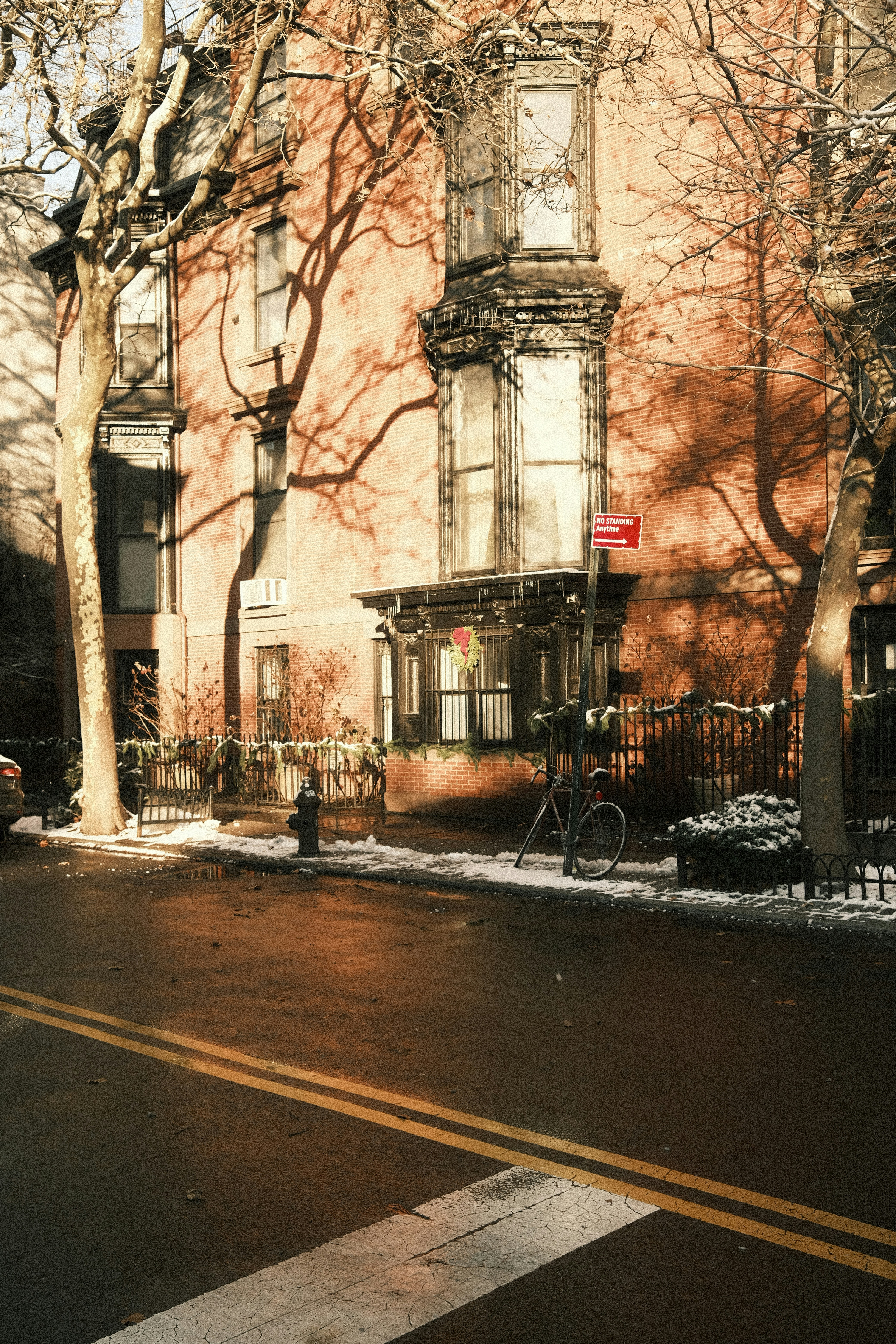 Brick building with bare trees and winter snow.