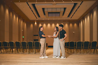 Three people standing in an empty conference room.