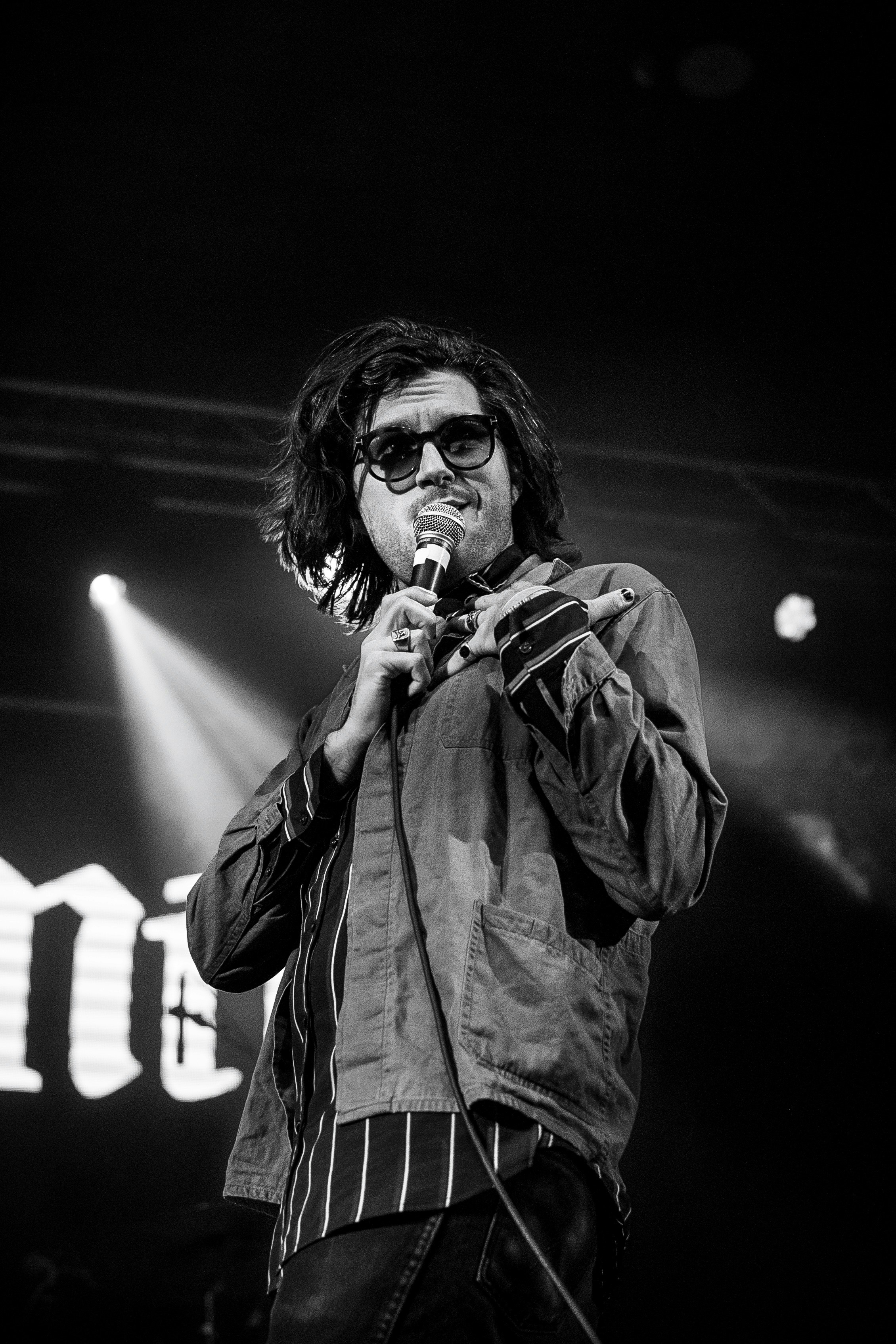 Uomo che canta davanti a un microfono sul palco.