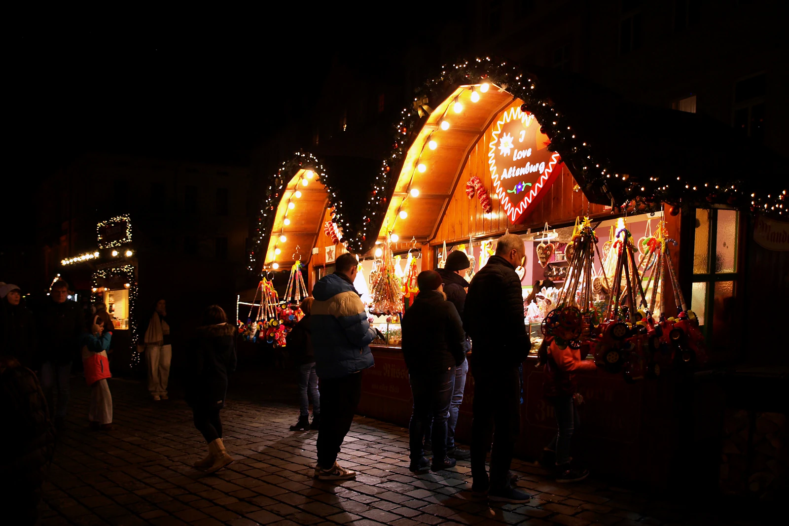 Menschen an einem festlich beleuchteten Weihnachtsmarktstand