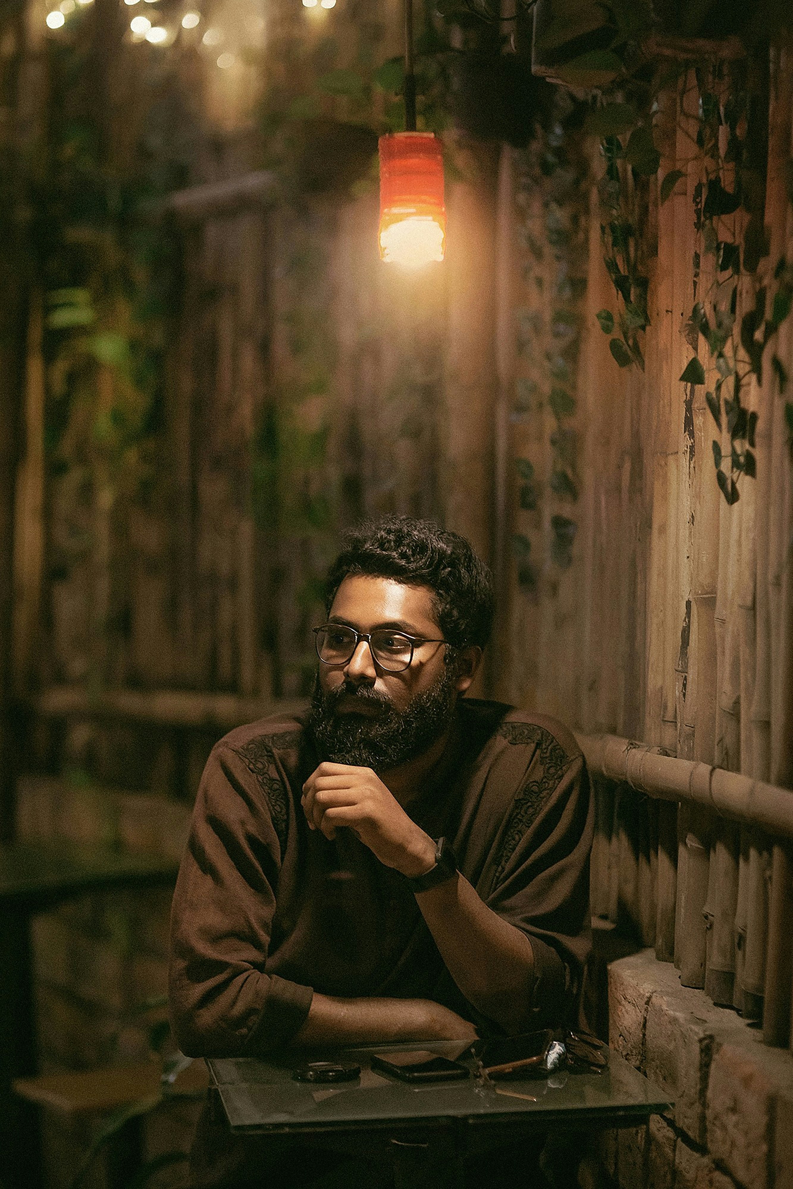 Man with beard wearing glasses in dimly lit cafe