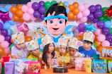 Children blowing out birthday candles with mascot.