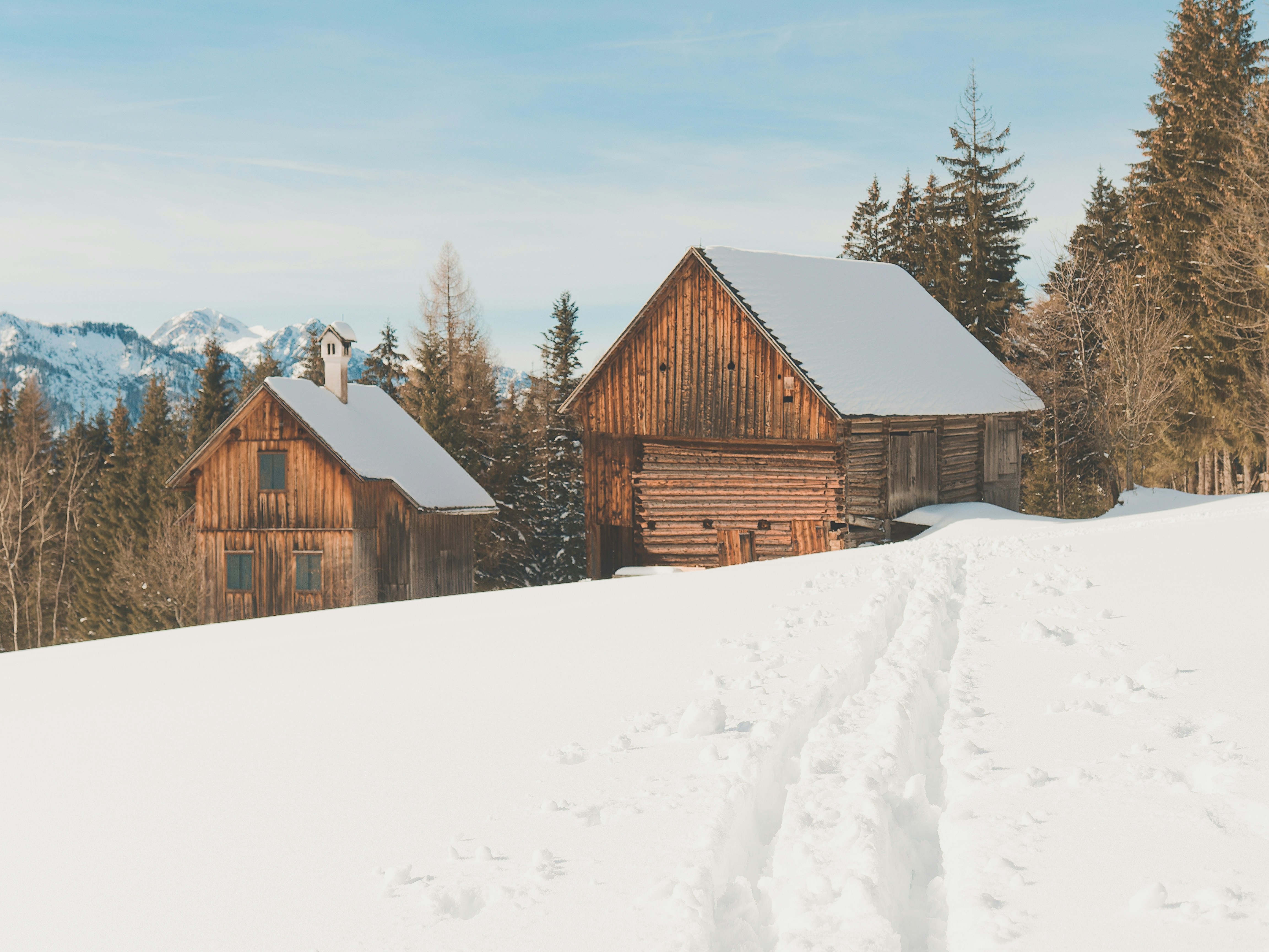 Two wooden cabins in a snowy mountain landscape.