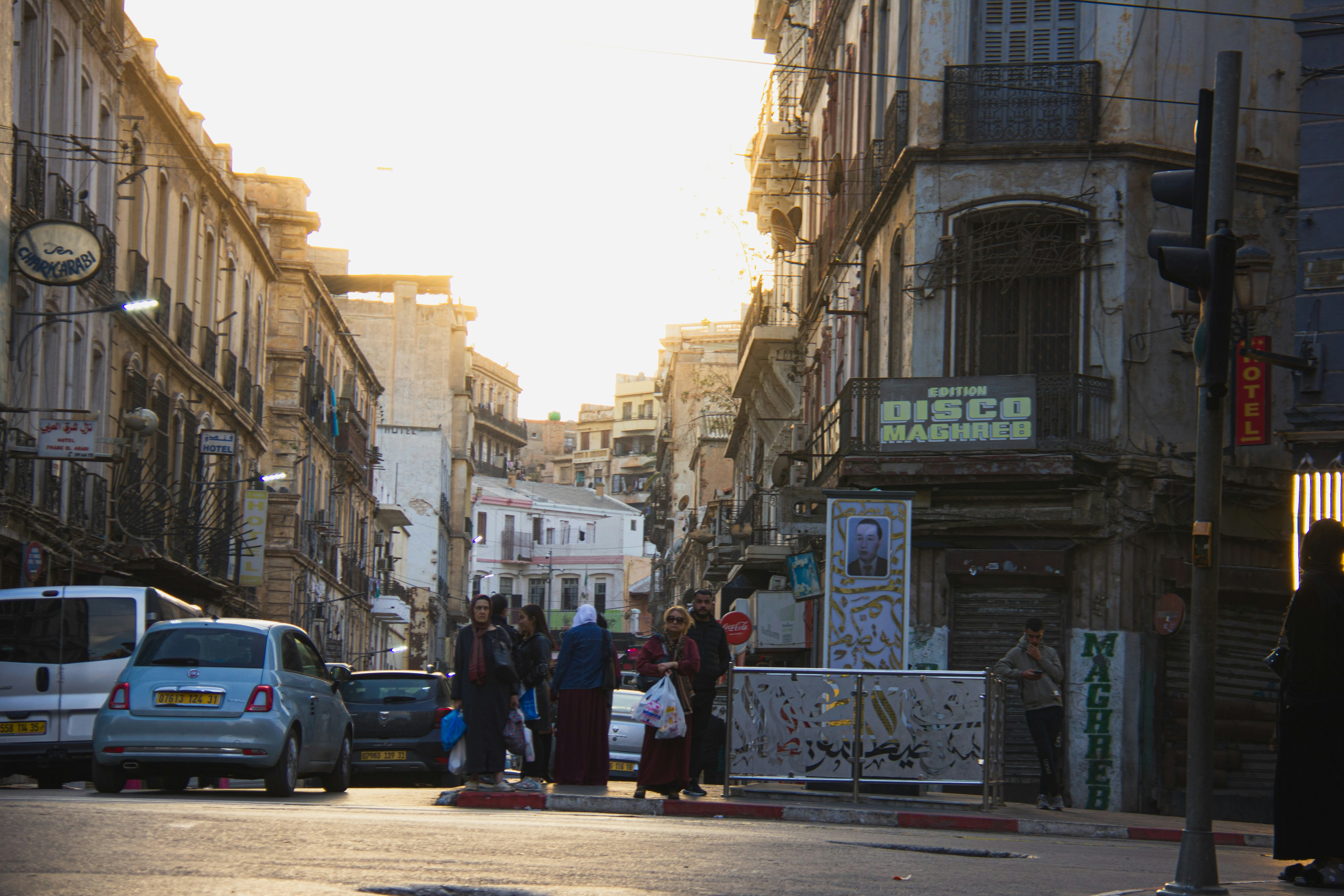 People crossing street in european city at sunset.