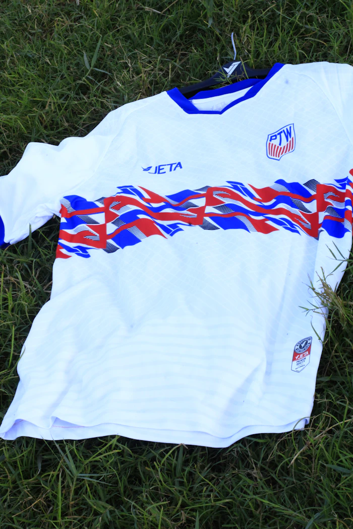 Wit voetbalshirt met rode en blauwe strepen op gras