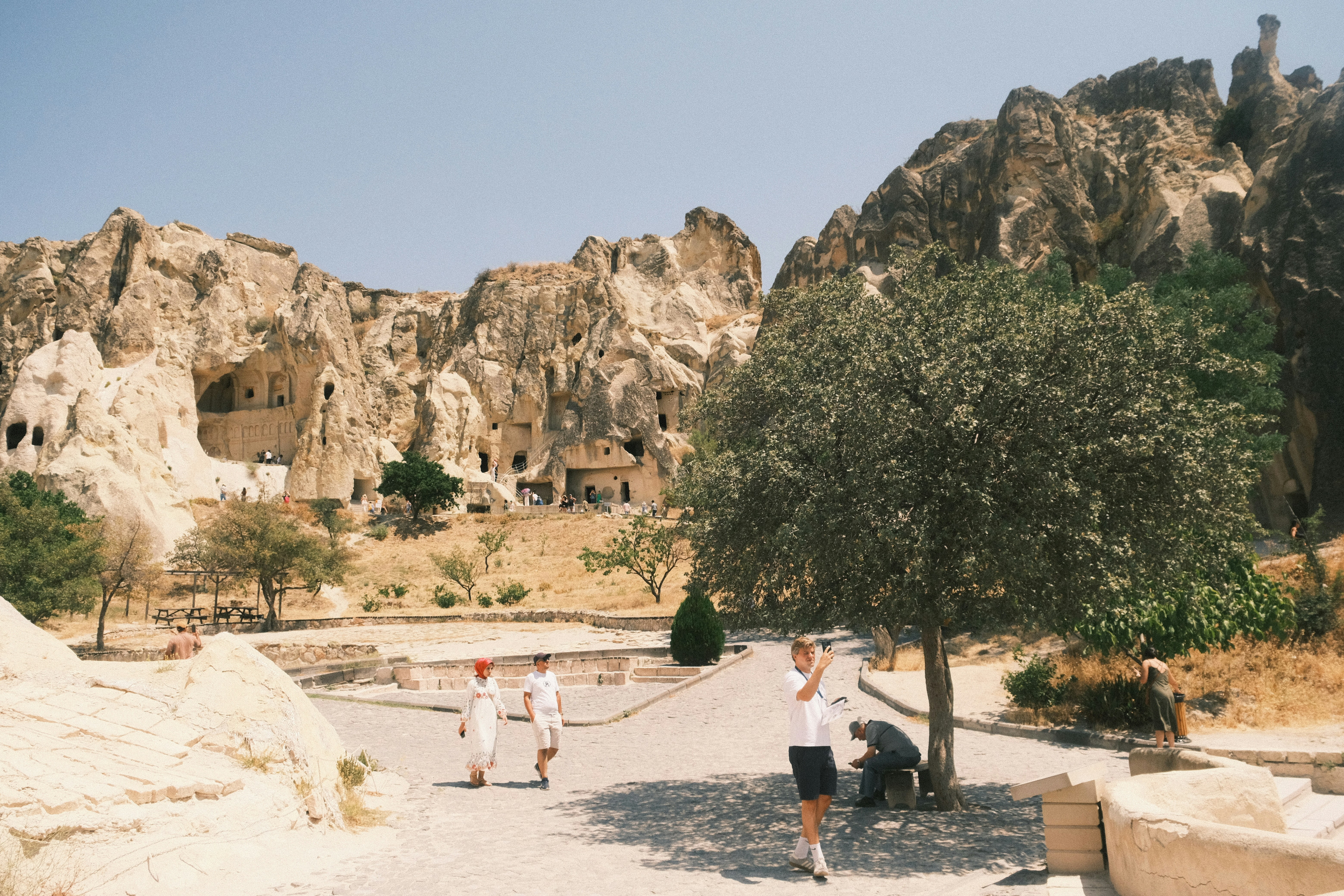 People walking through a rocky, cave-filled landscape.