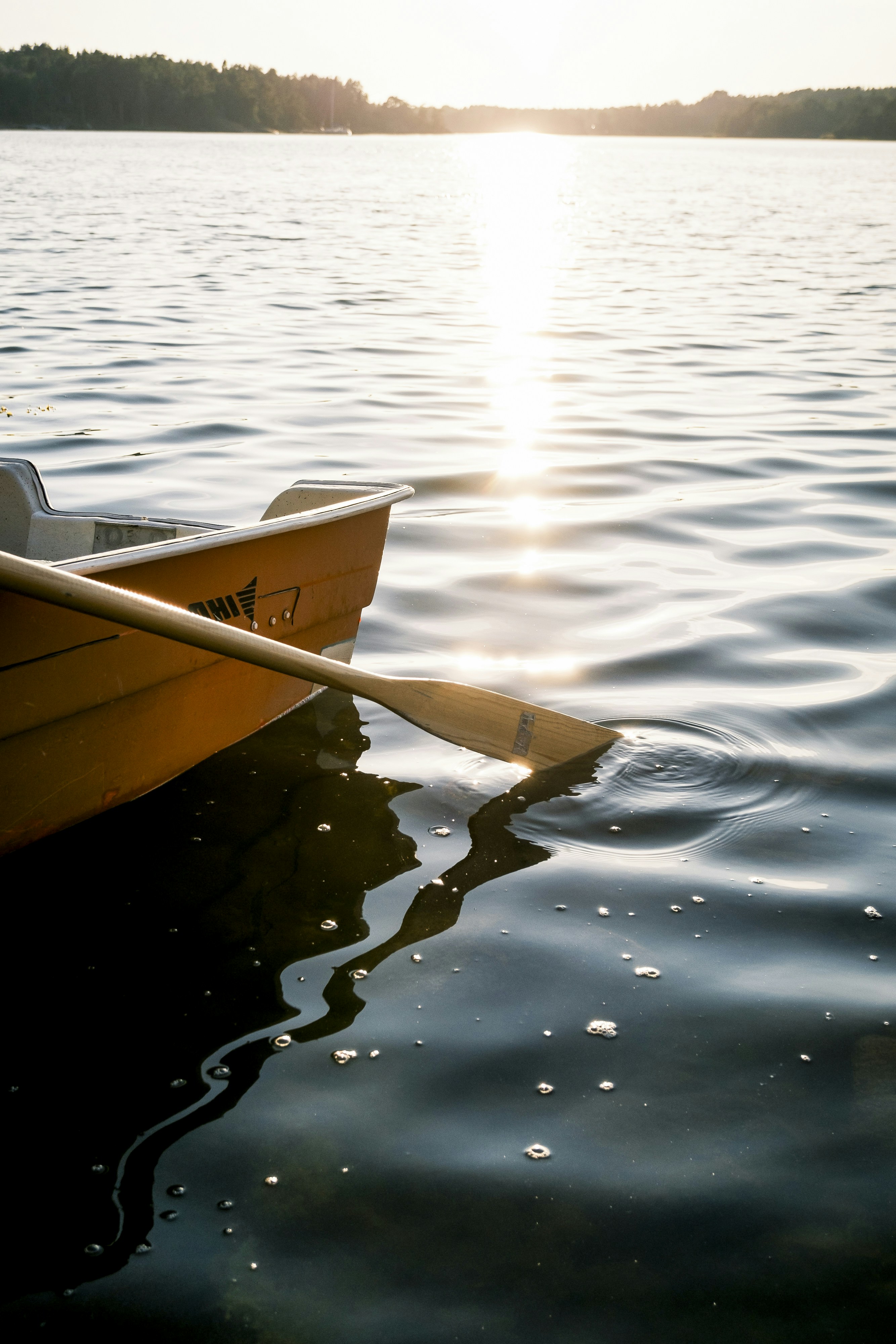 夕暮れの静かな湖に漕がれたオレンジ色のボート。
