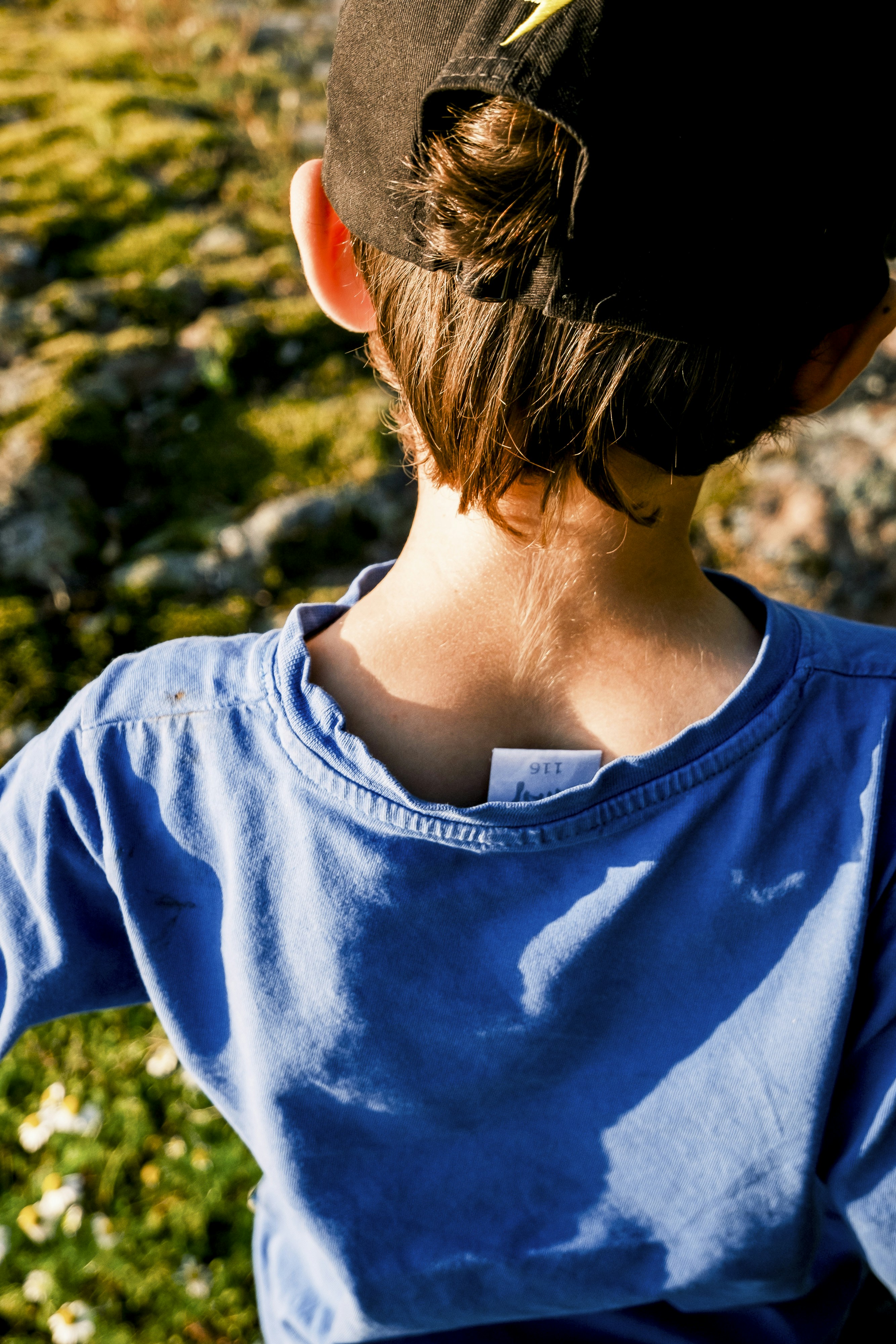 青いシャツと黒い帽子をかぶった幼い子供。