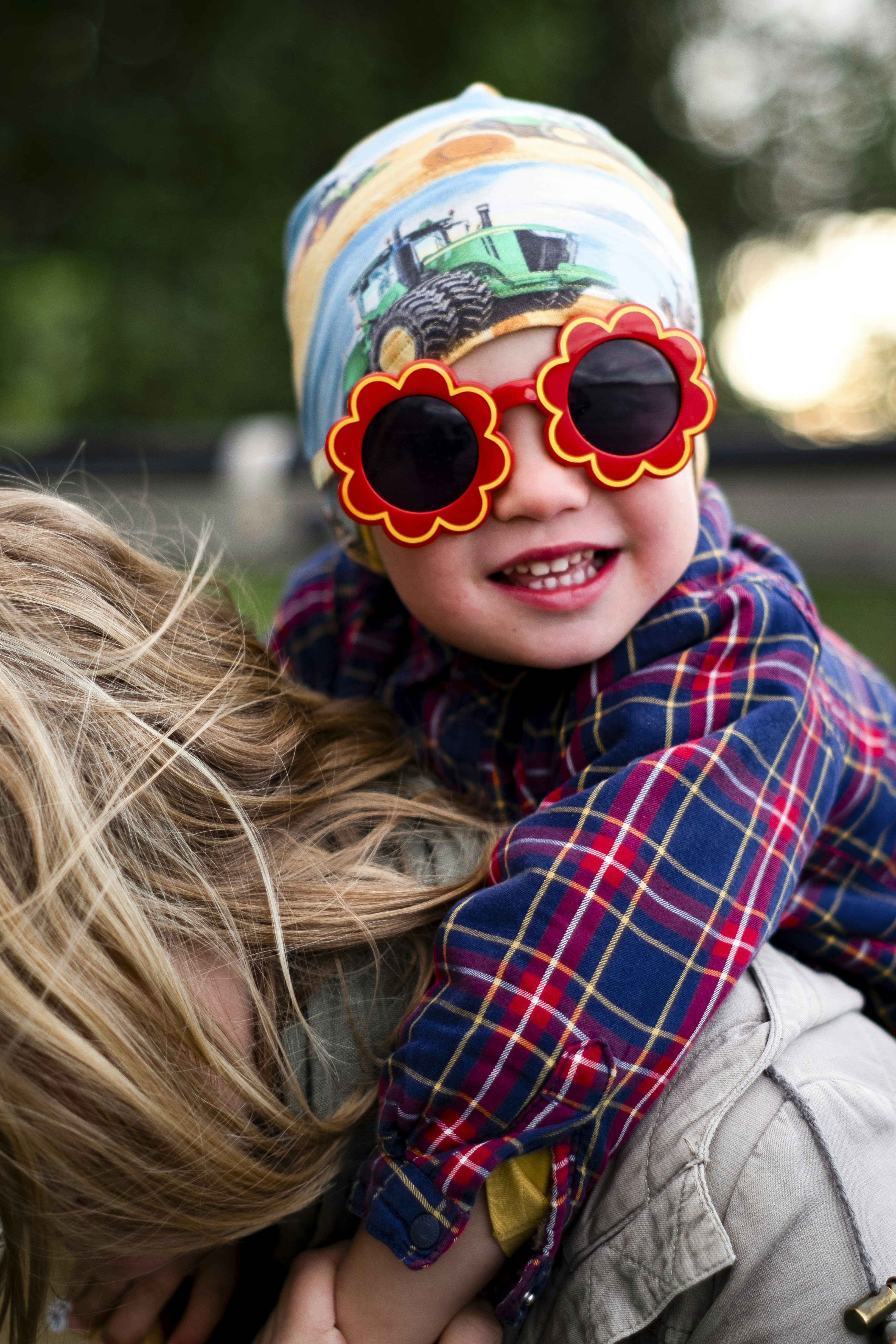 帽子と花のサングラスをかぶった笑顔の子供。