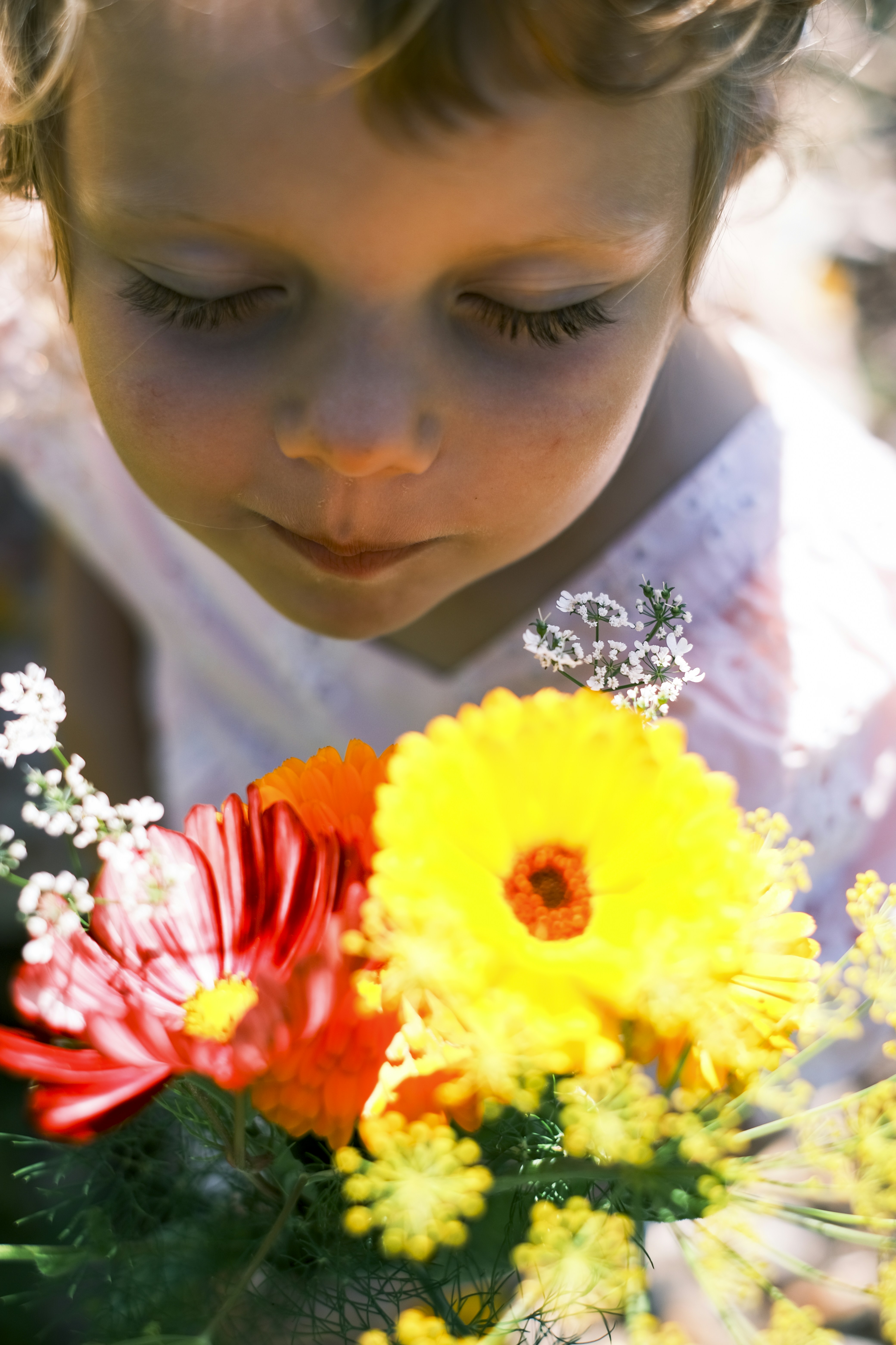 色とりどりの花束の香りを嗅ぐ若い少女