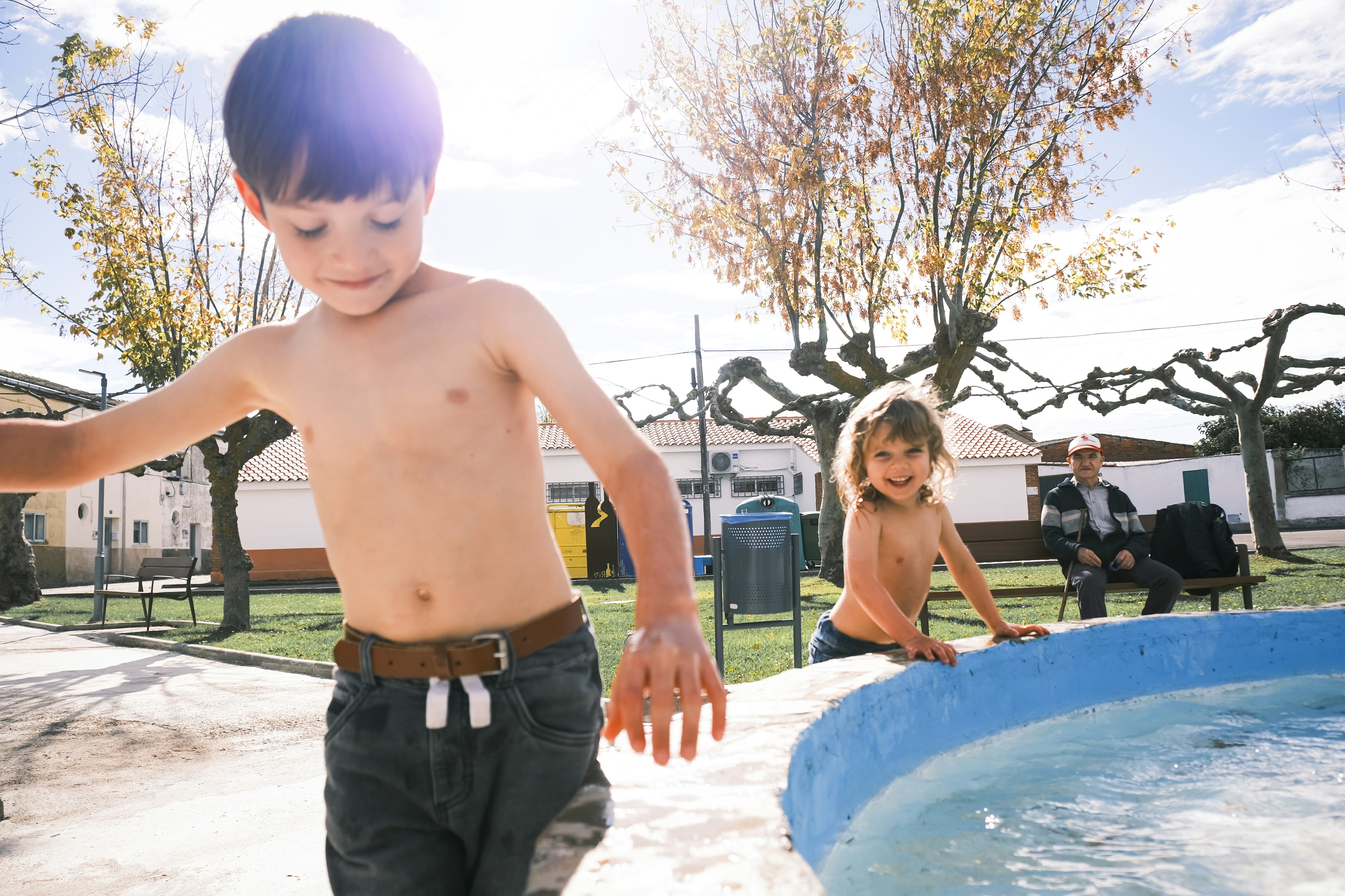 噴水のそばで遊ぶ二人の上半身裸の子供