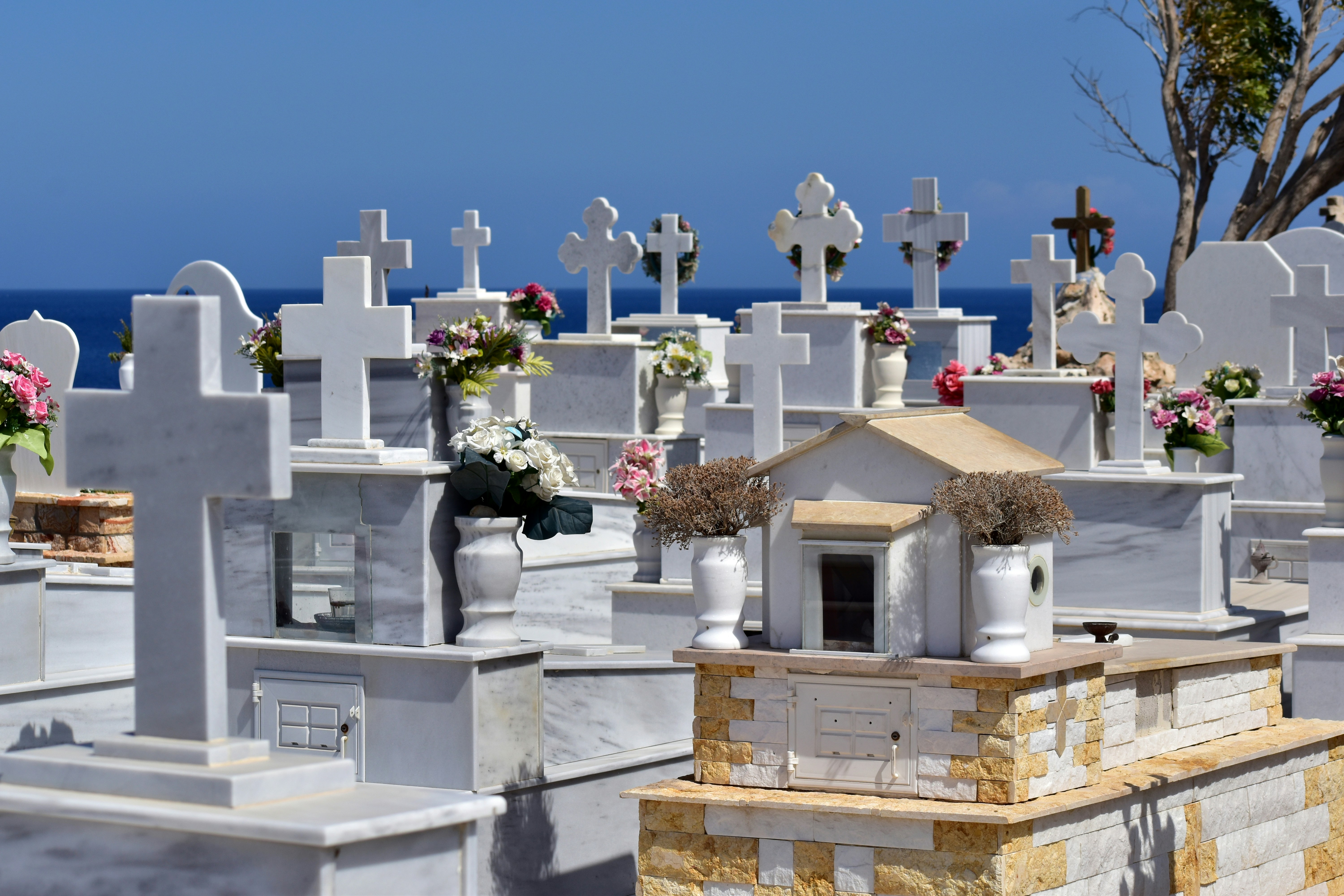 White marble gravestones with flowers by the sea.