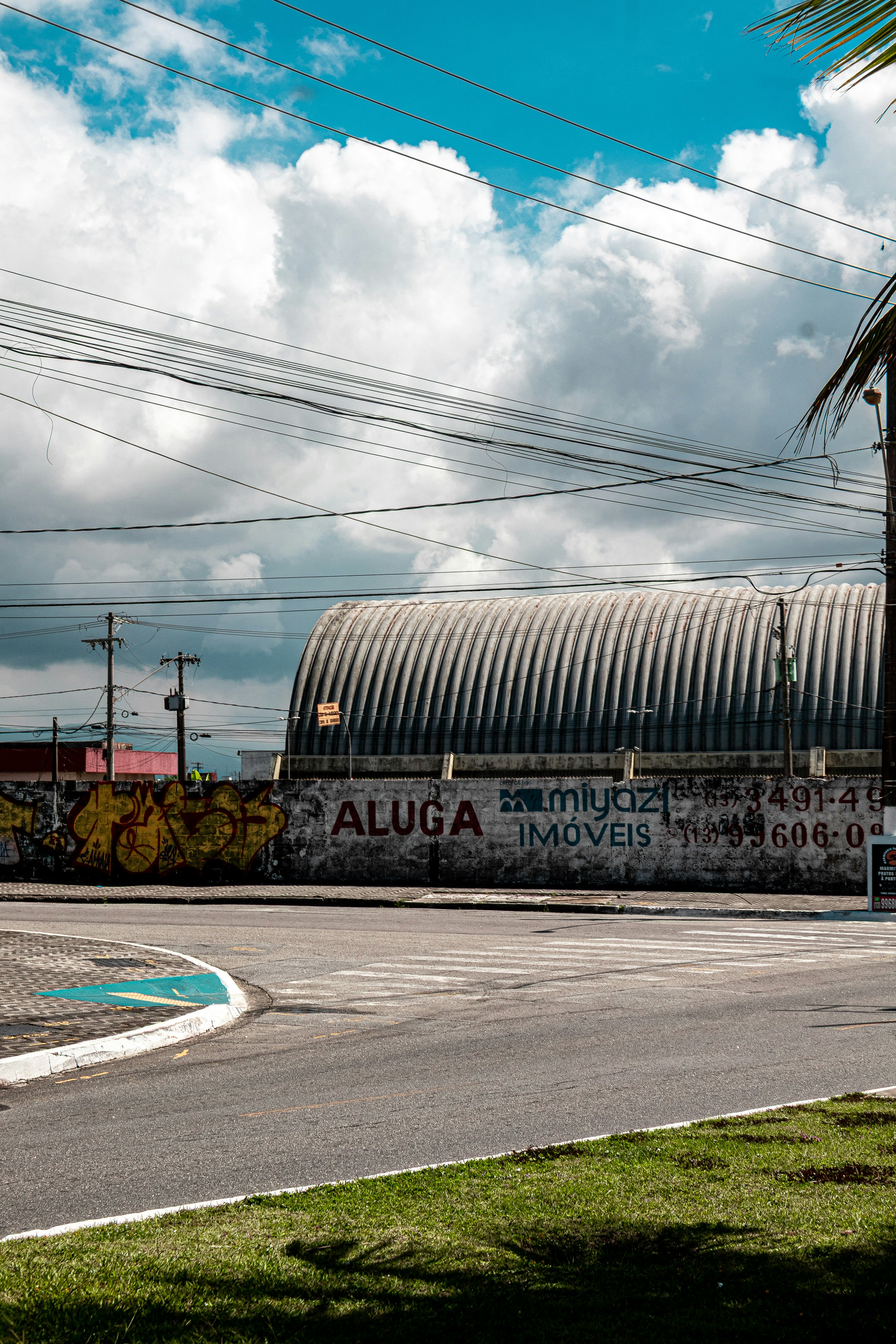 Curved metal building behind a graffiti-covered wall.