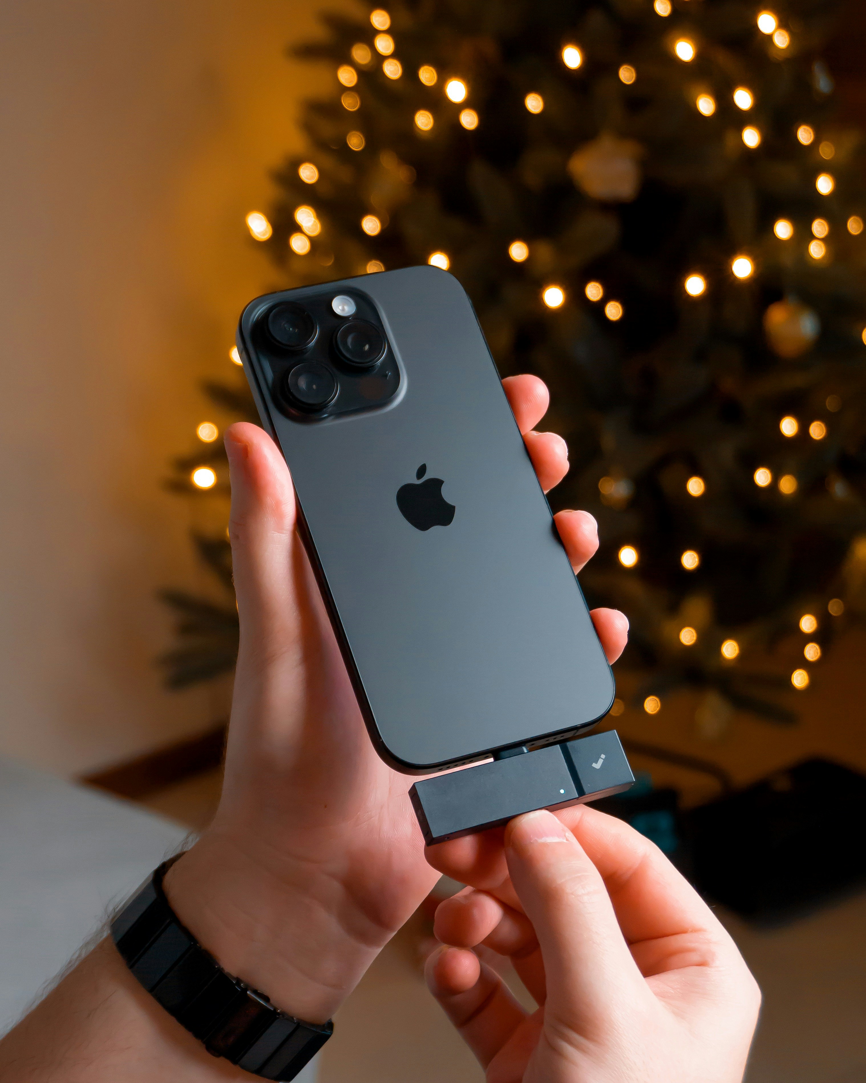 Hands holding iPhone with christmas tree lights bokeh