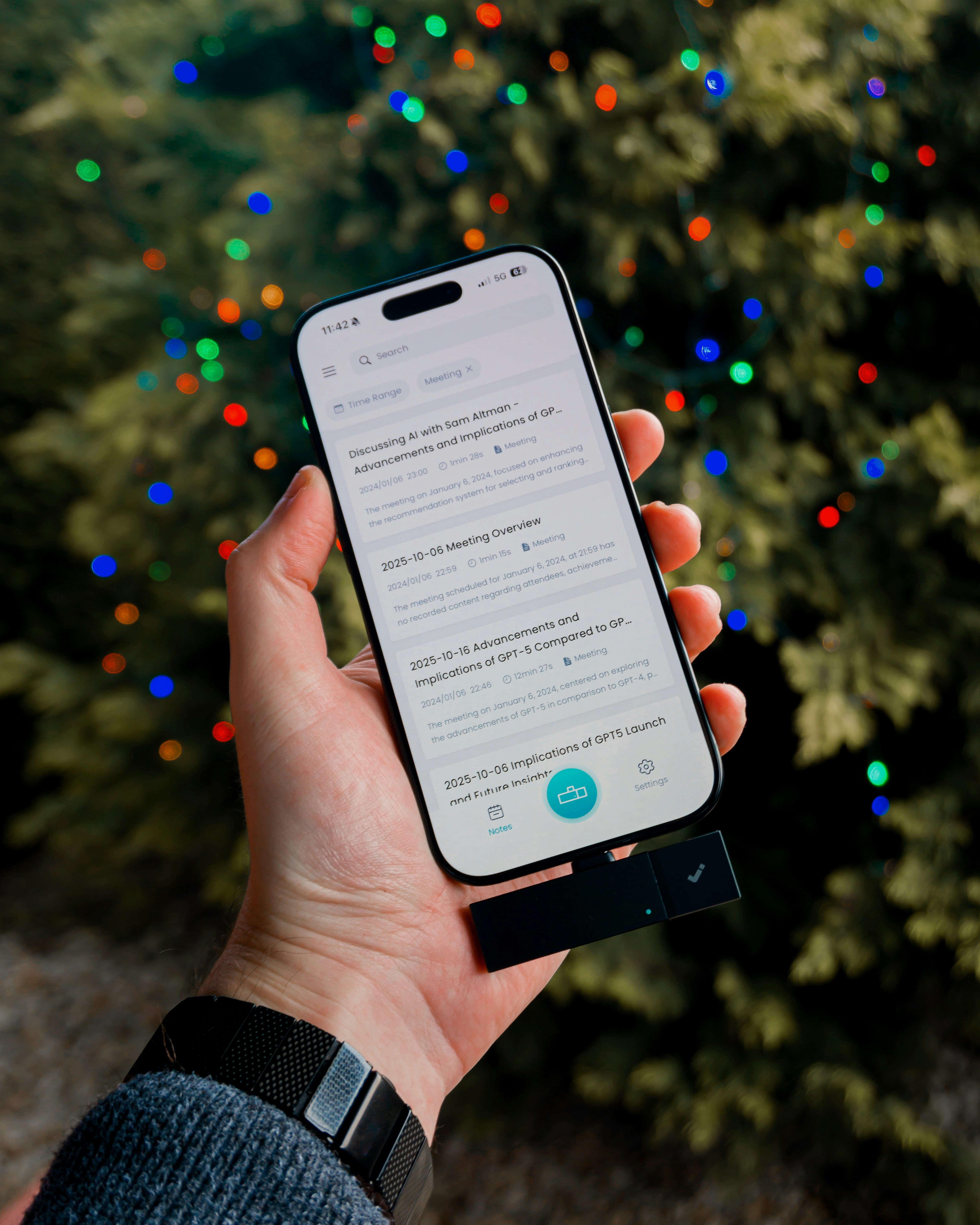 Hand holding smartphone with news articles and christmas lights.