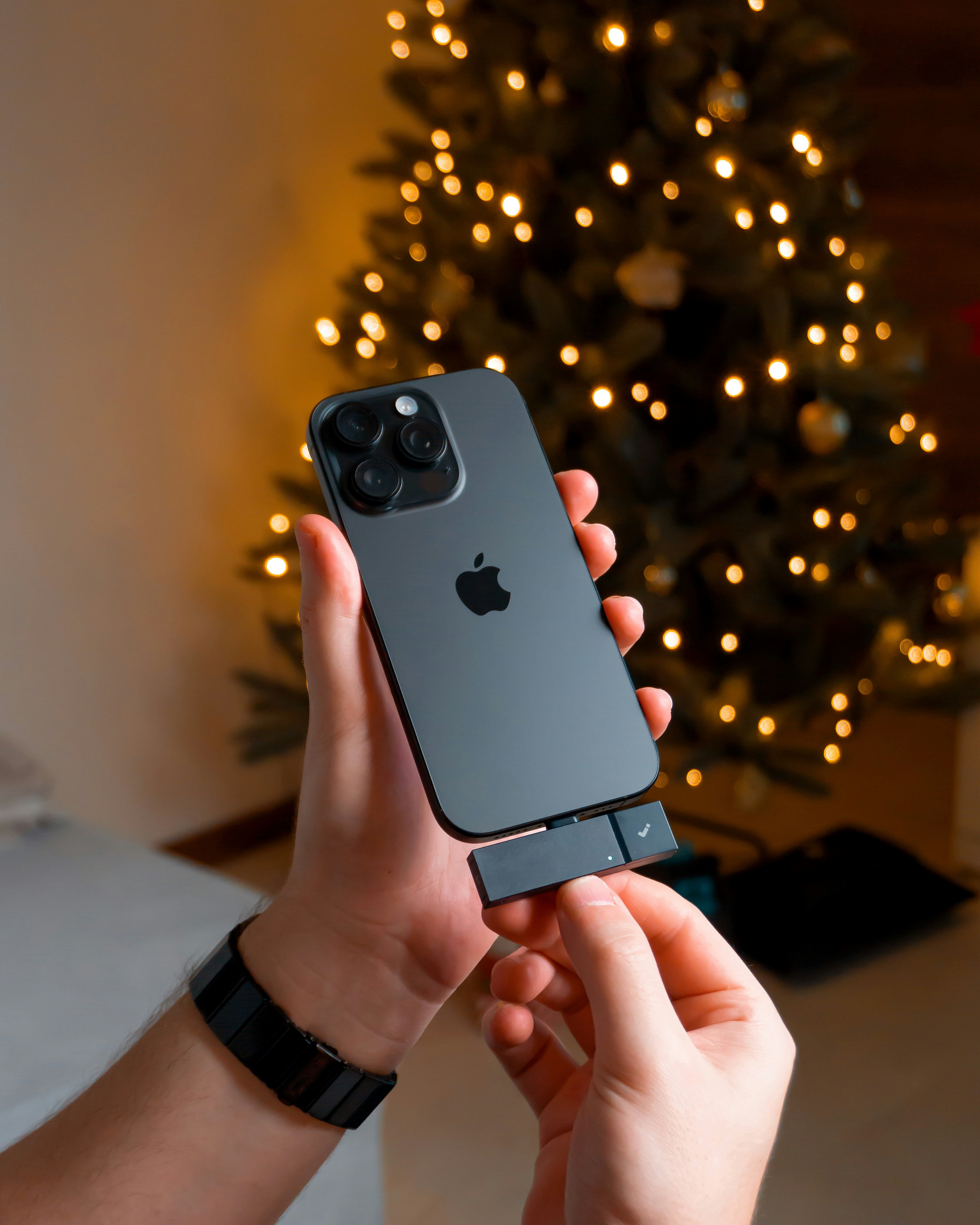 Hands holding a smartphone with a christmas tree background
