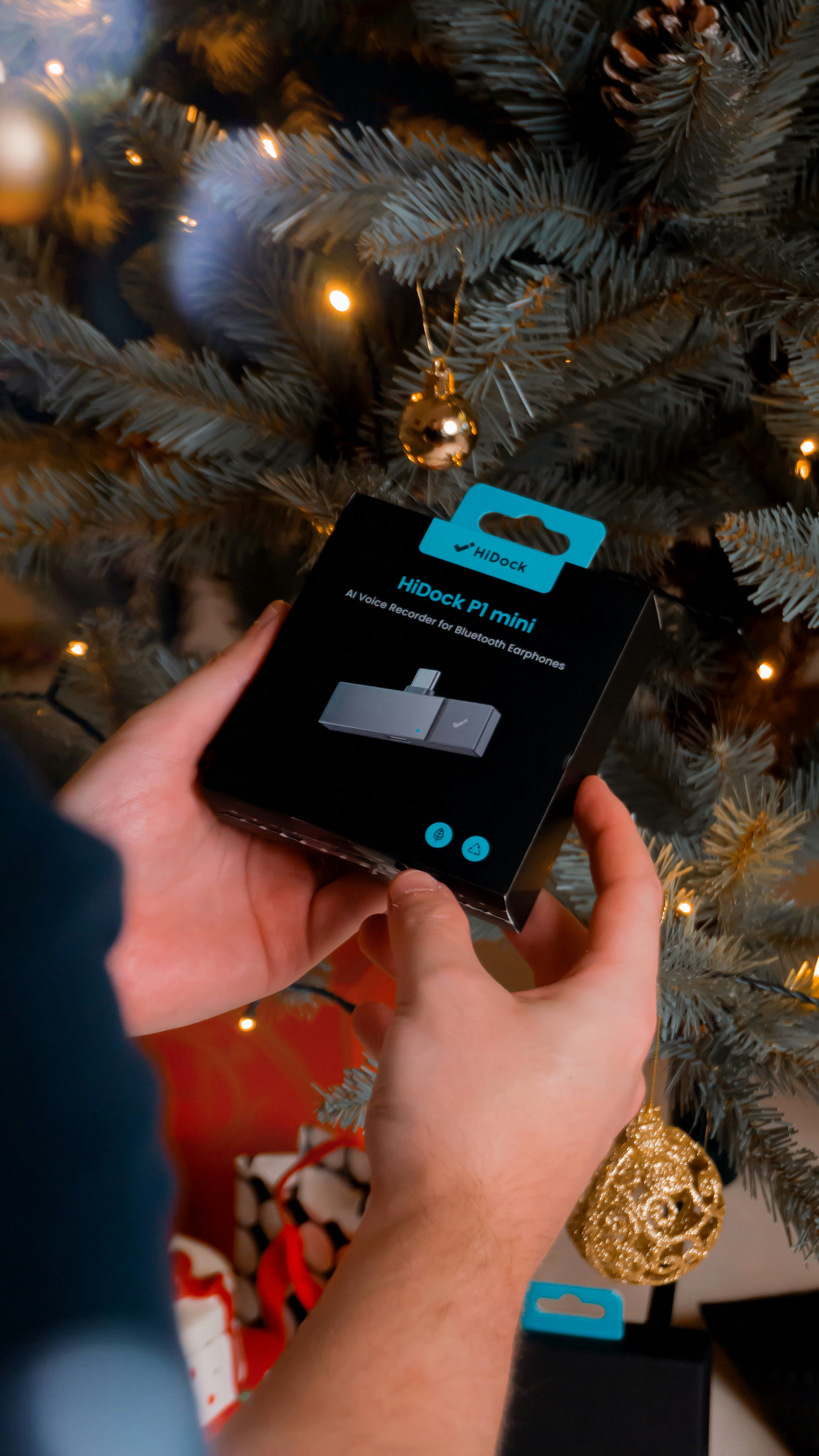 Hands hold product box near decorated christmas tree
