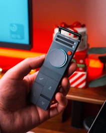 Hand holding a modern gray remote control