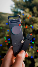 Hand holding a remote control with christmas lights.