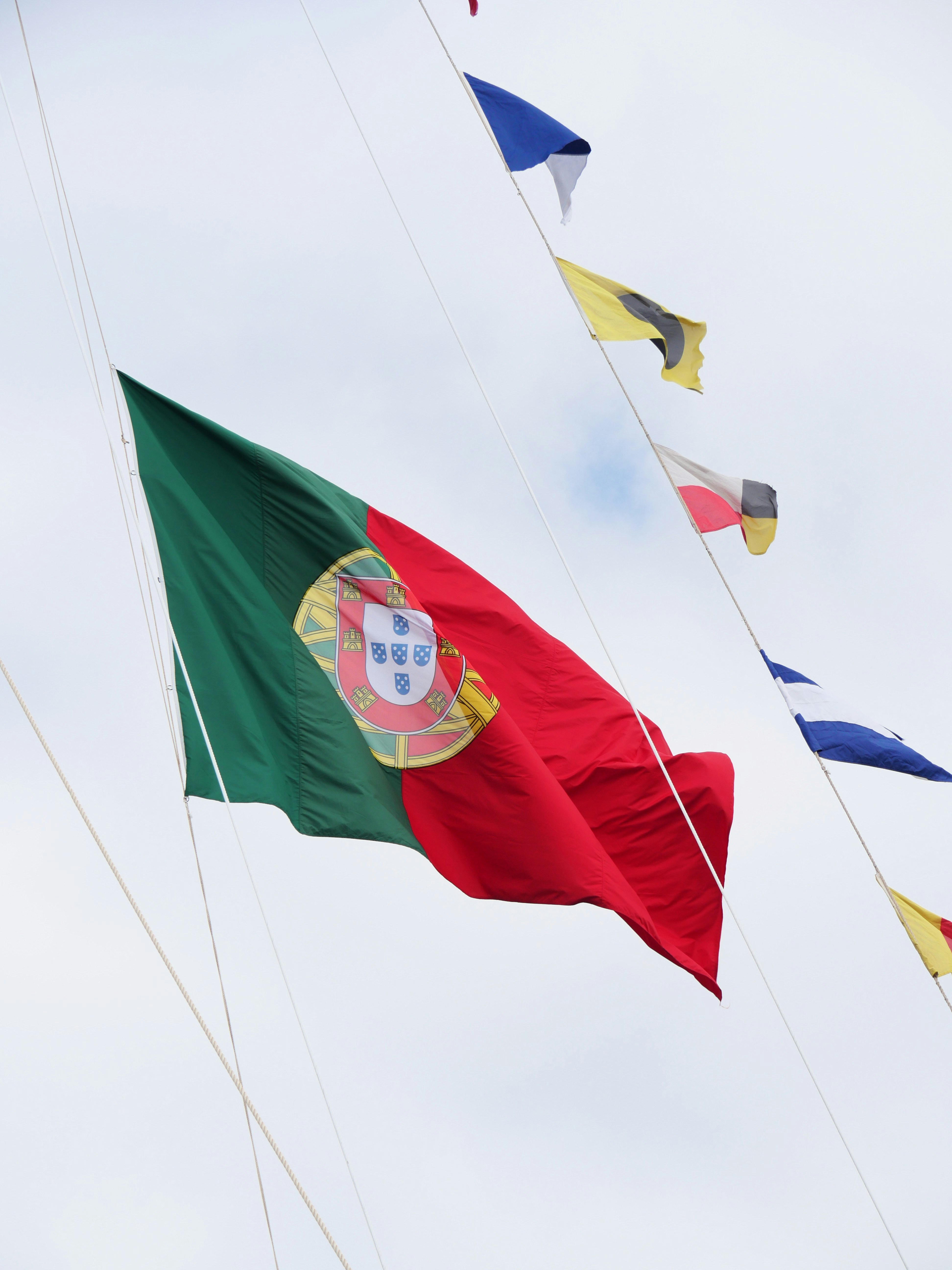 The portuguese flag flies against a cloudy sky.