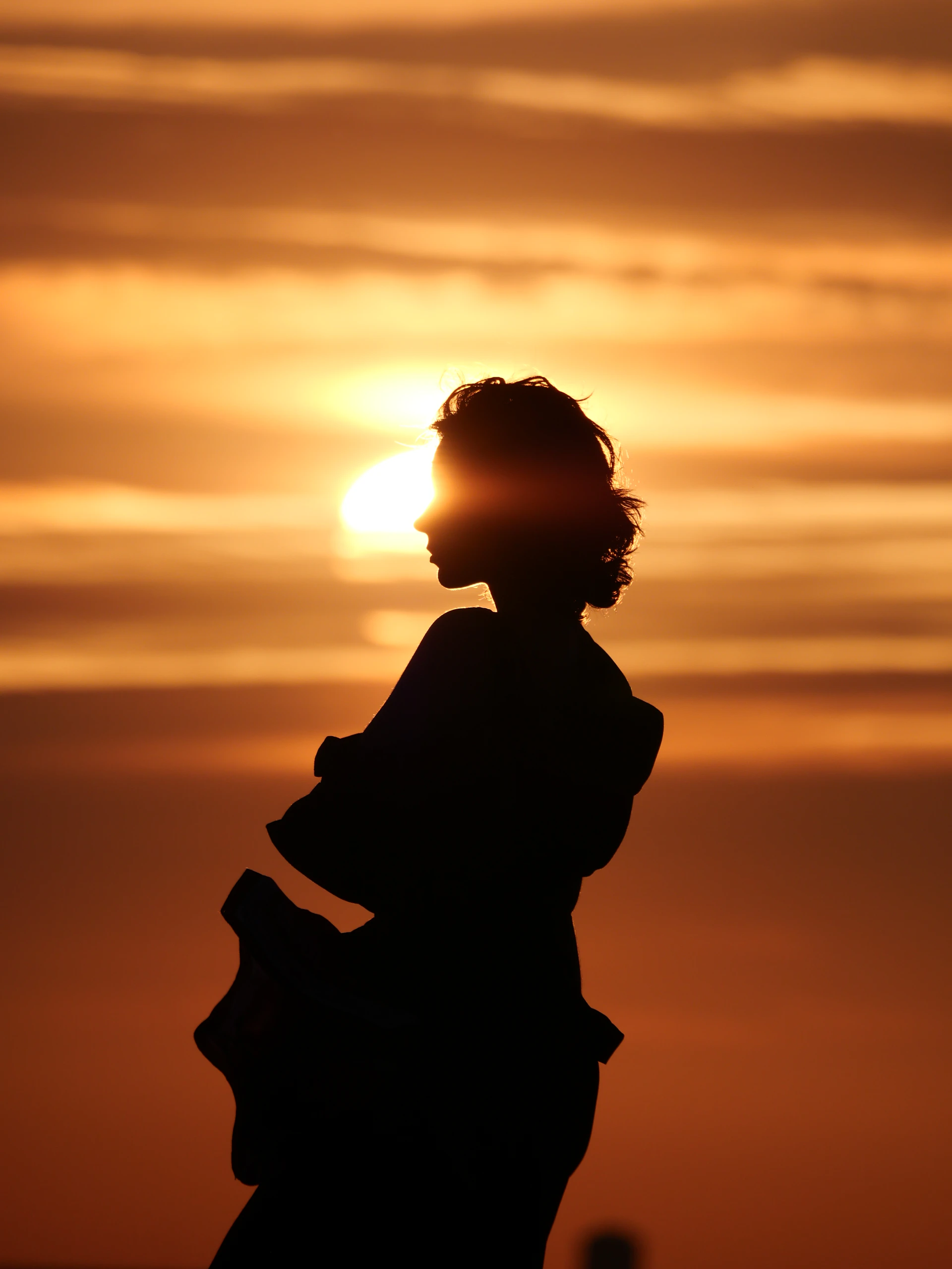 Silhouette of a woman against a bright sunset