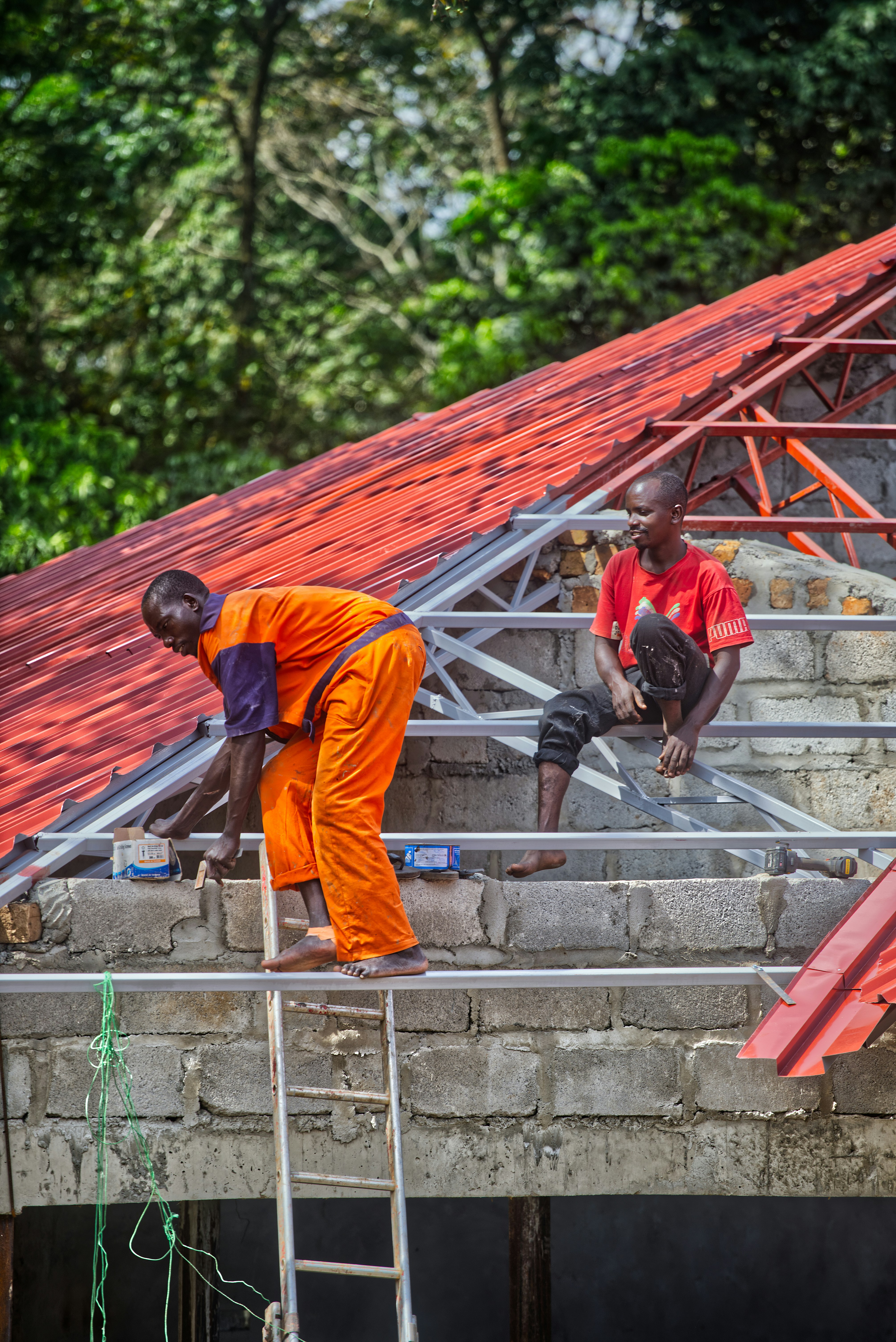 Two men working on a red roof construction site.