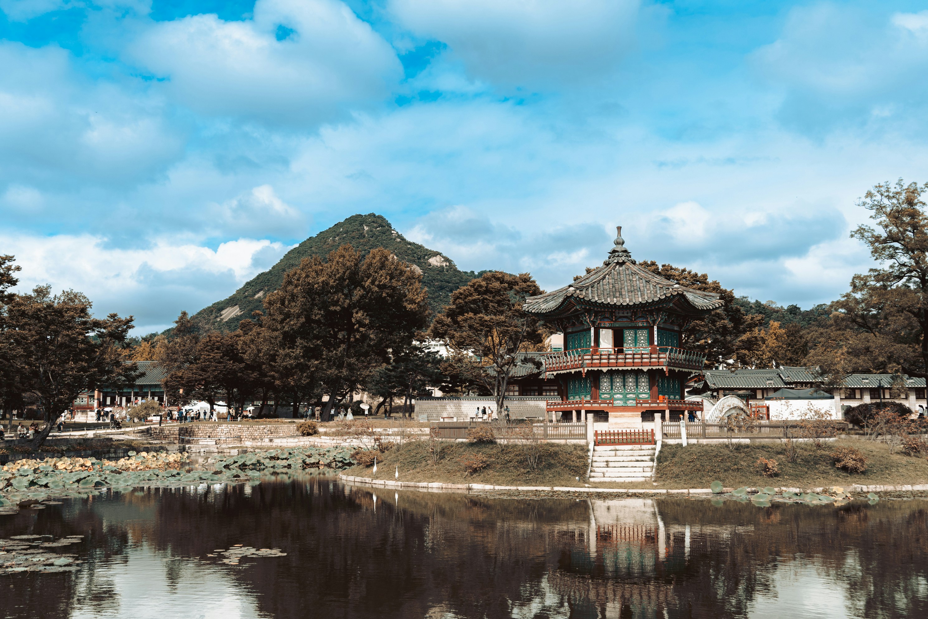 Traditional korean pavilion reflected in water with mountain background.