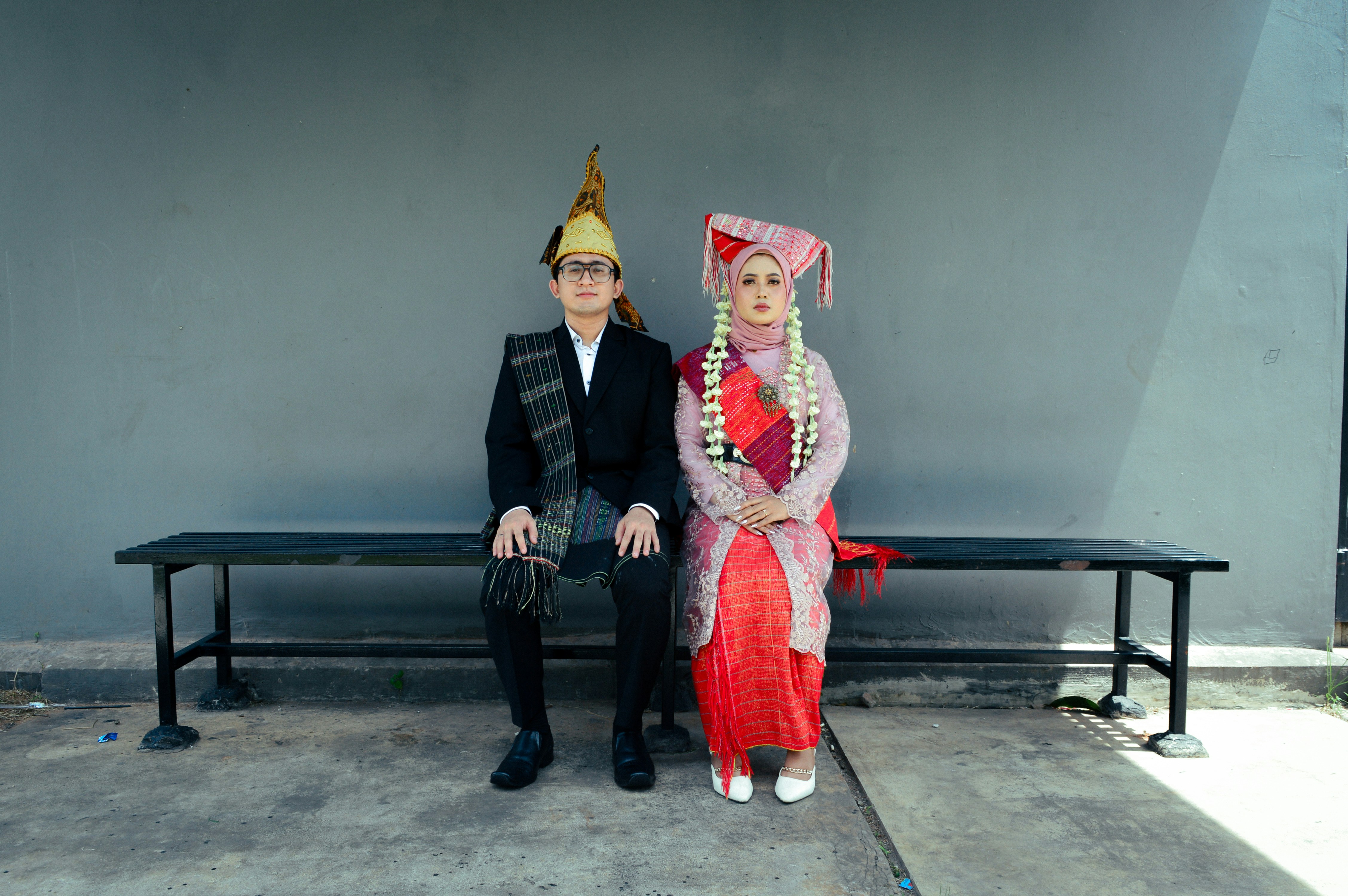 Couple in traditional attire sitting on a bench