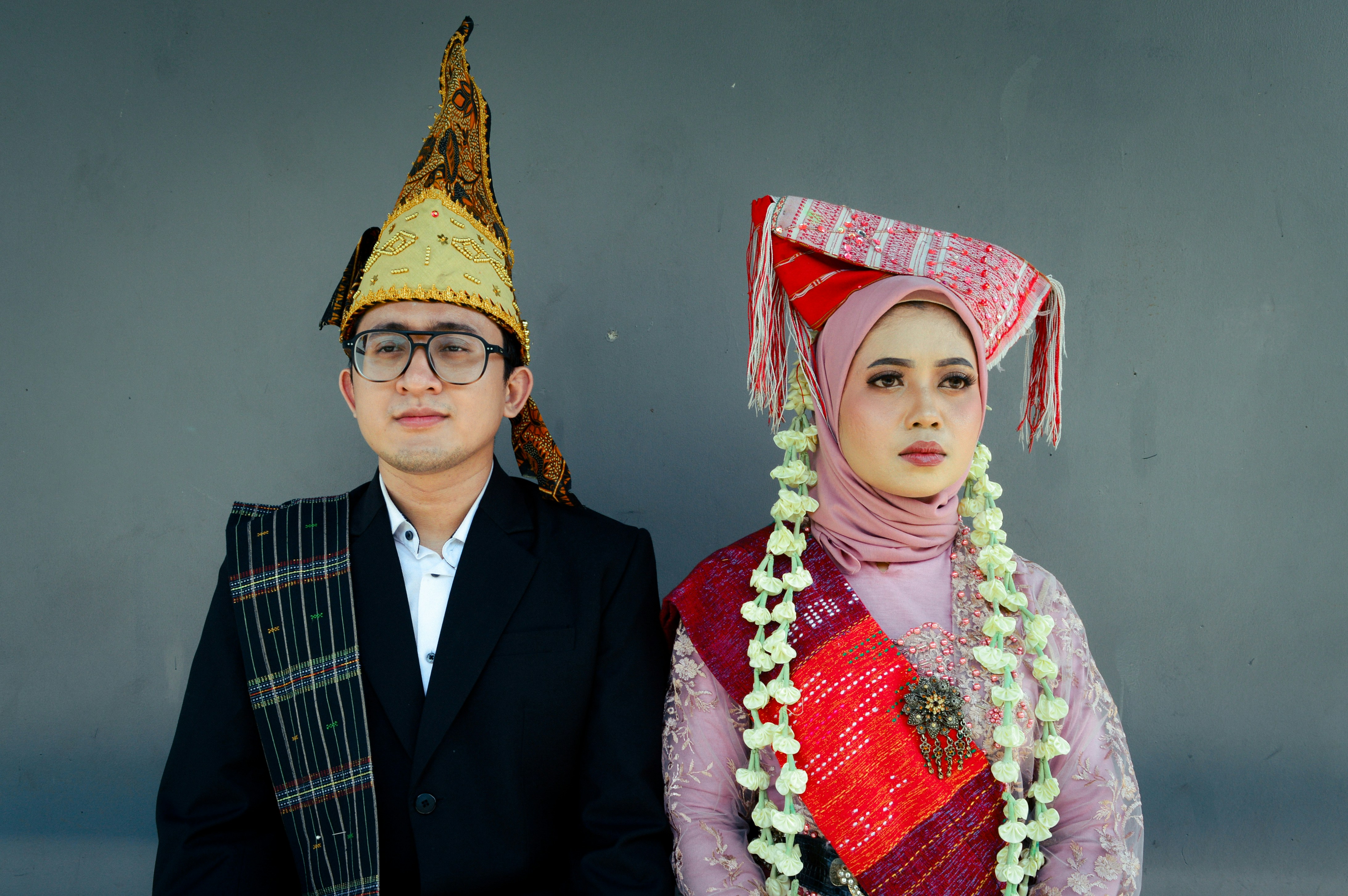 Couple in traditional attire against a gray background