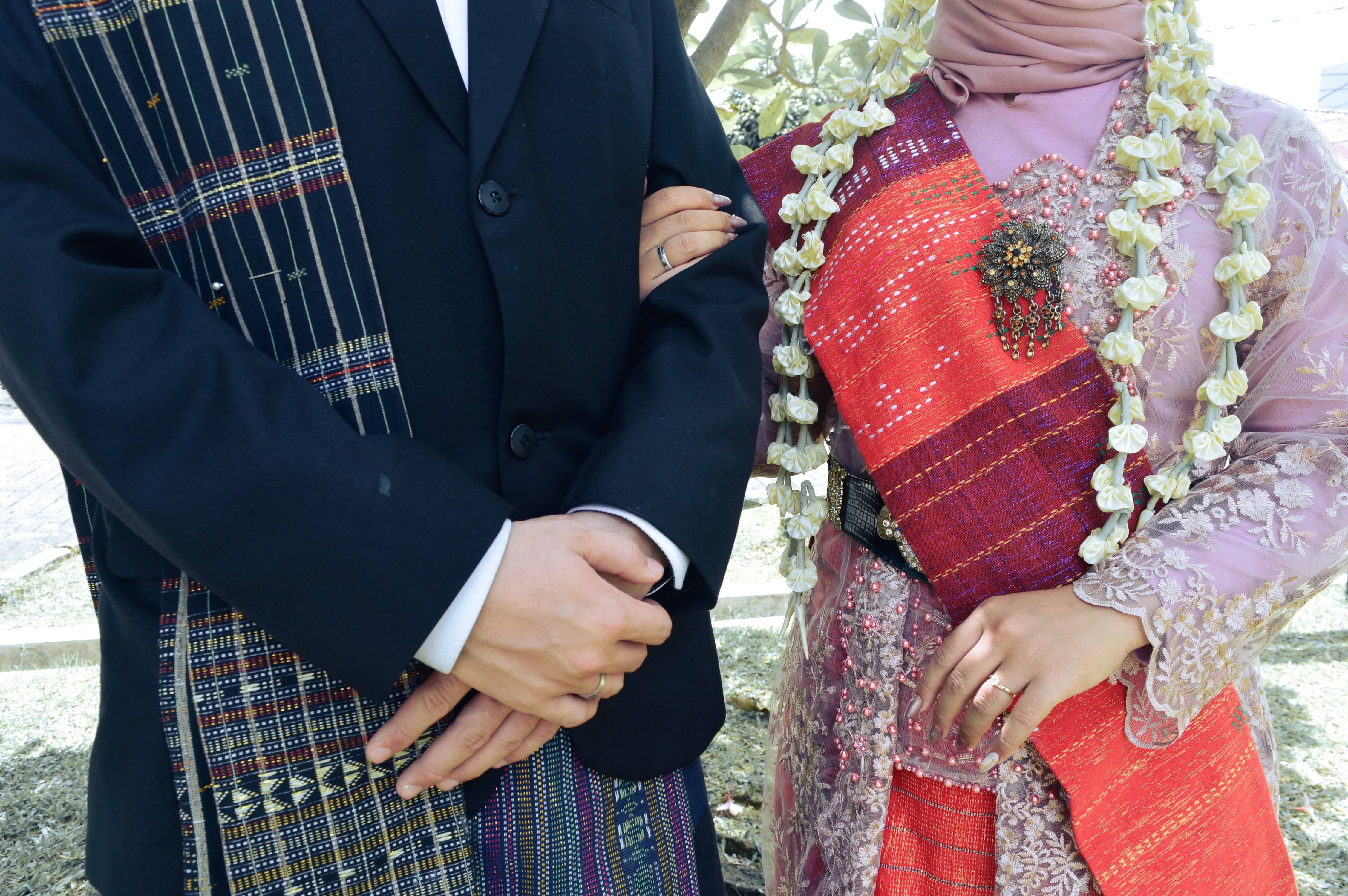 Couple in traditional wedding attire arm in arm.