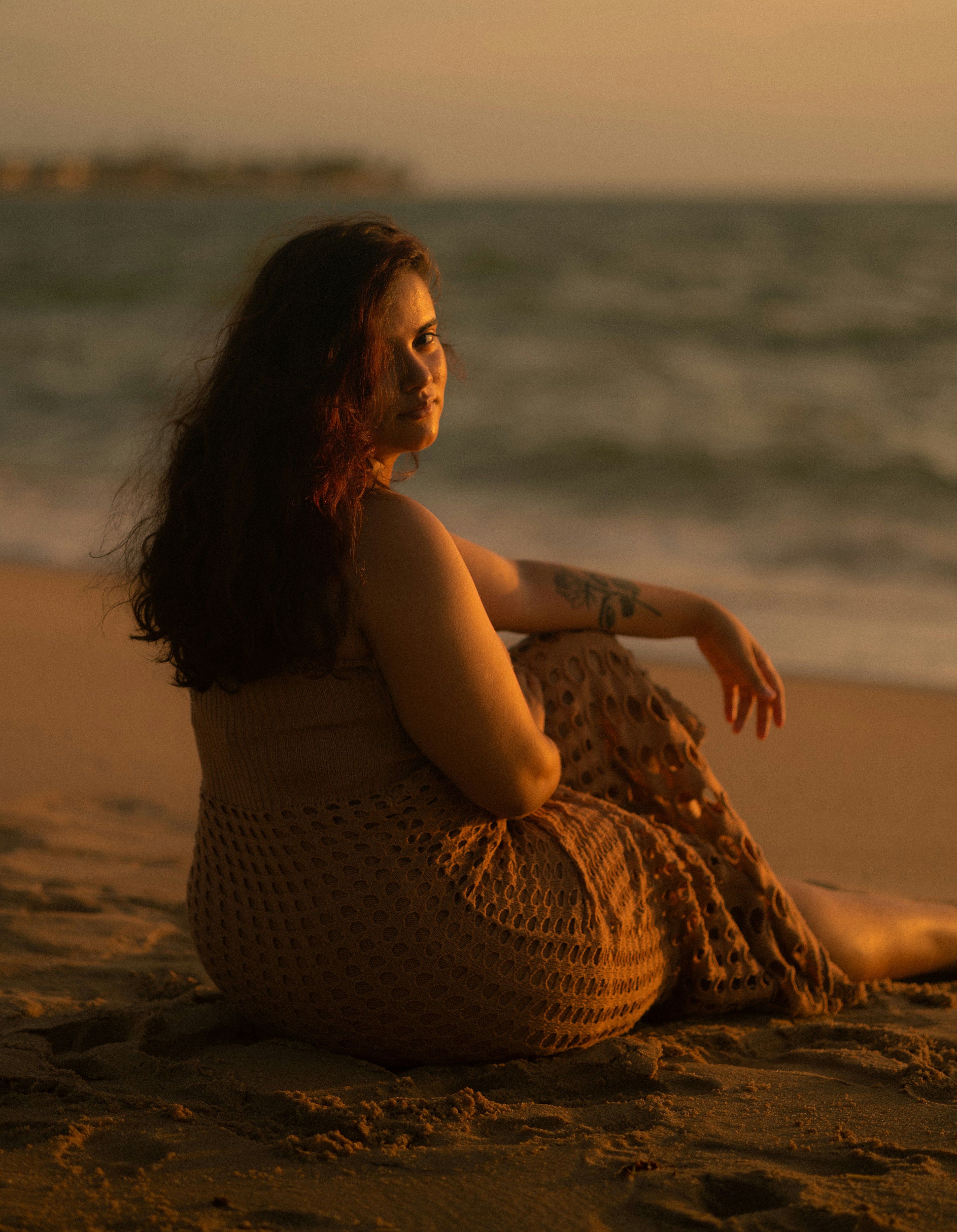 Woman sitting on a beach at sunset
