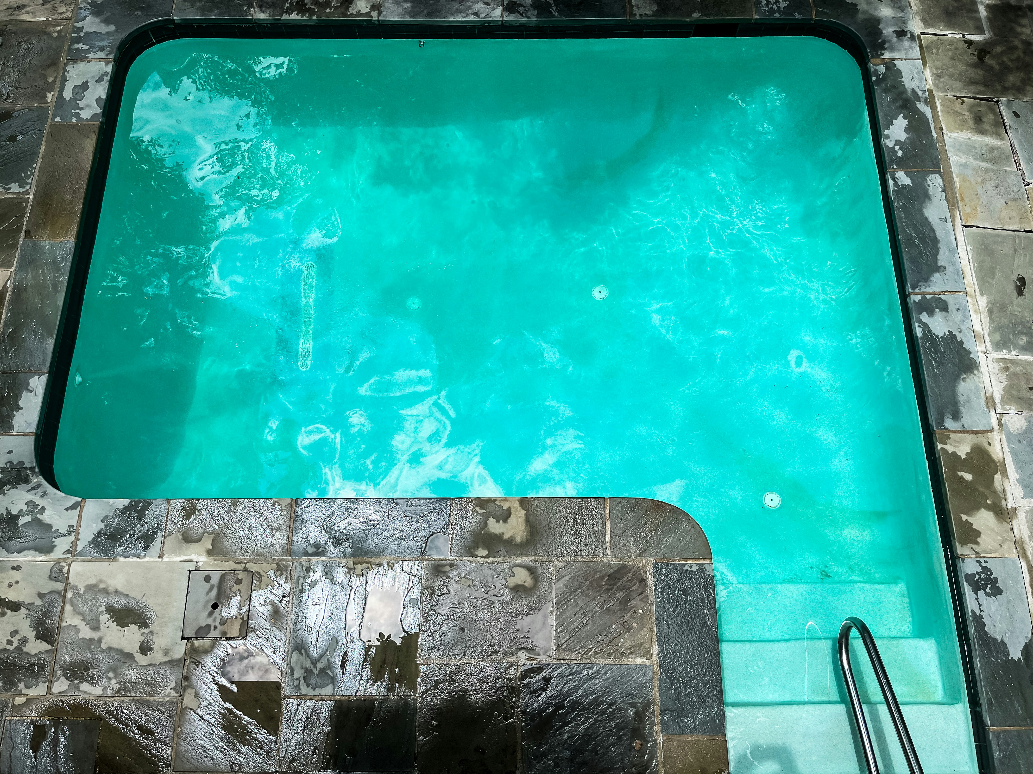 A clean, empty swimming pool with turquoise water.