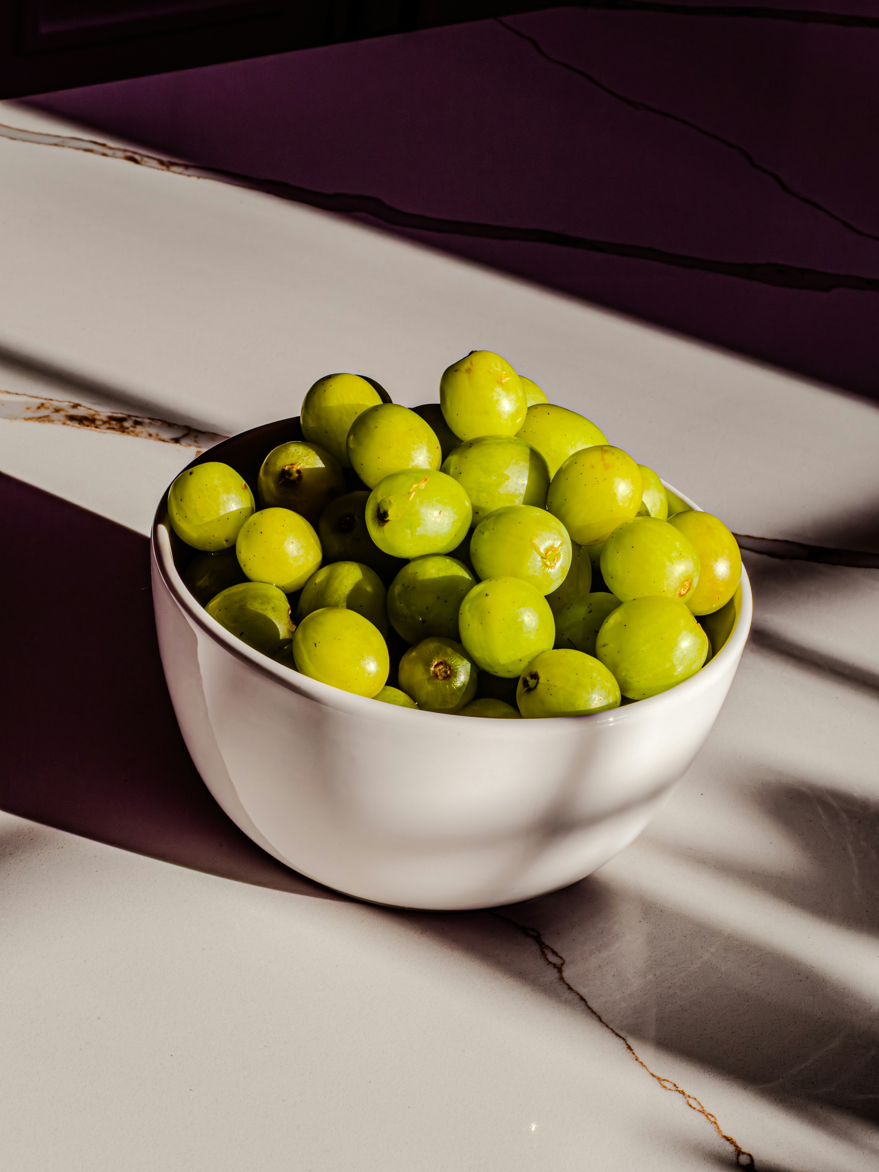 A white bowl filled with fresh green grapes