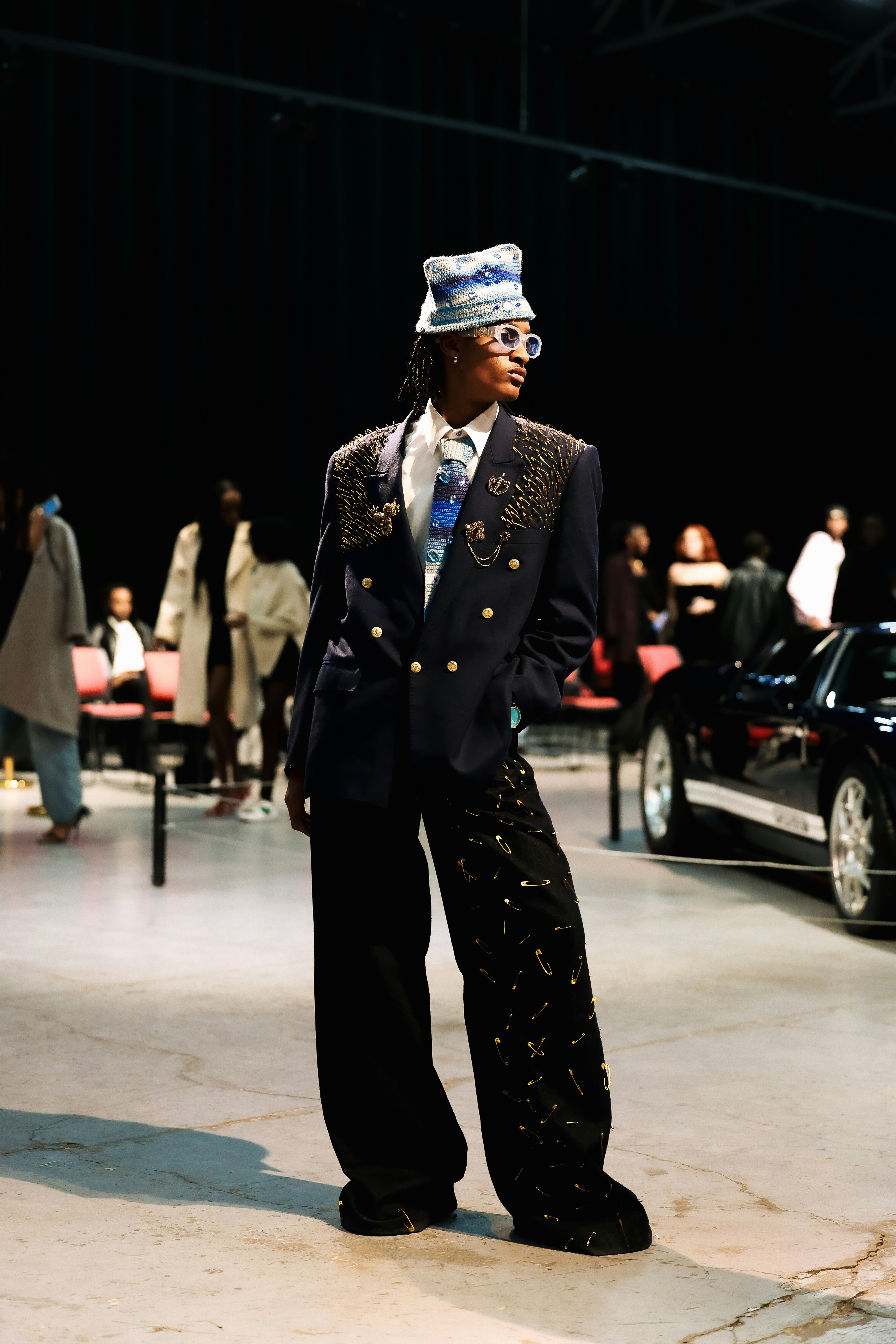 A person in a stylish outfit stands on a runway.