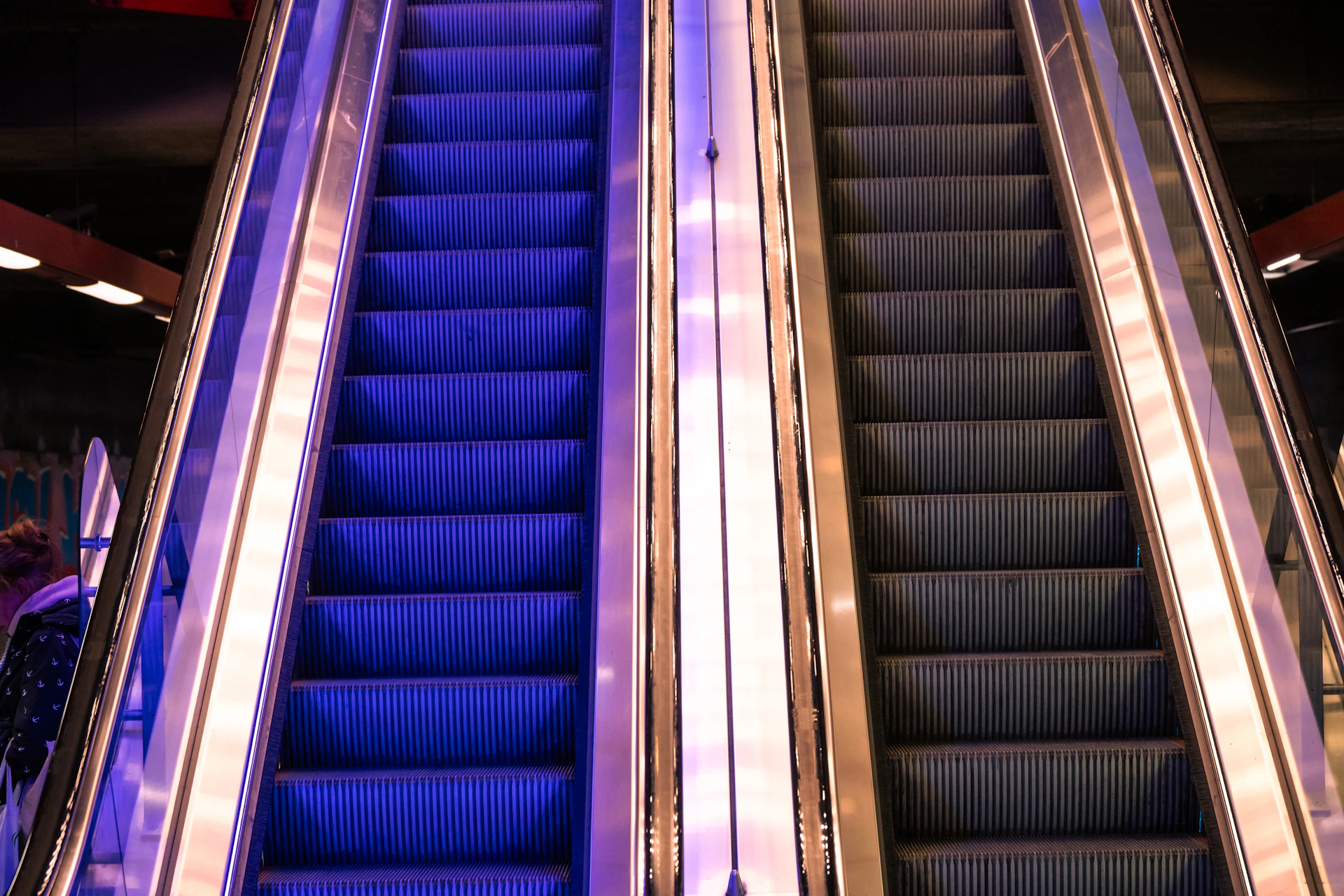 Two escalators, one lit blue, the other dark.
