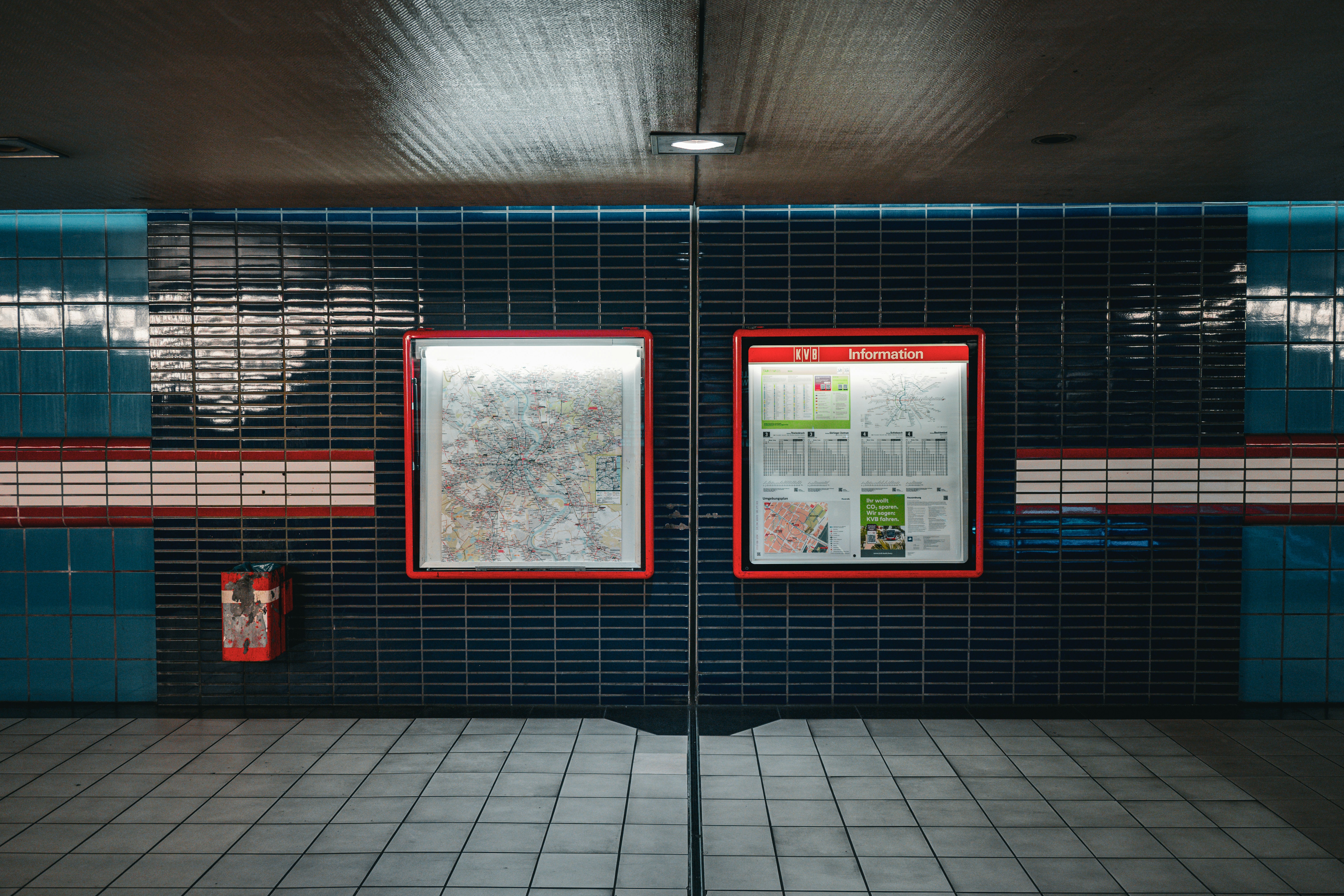 Two illuminated displays on a tiled subway station wall.