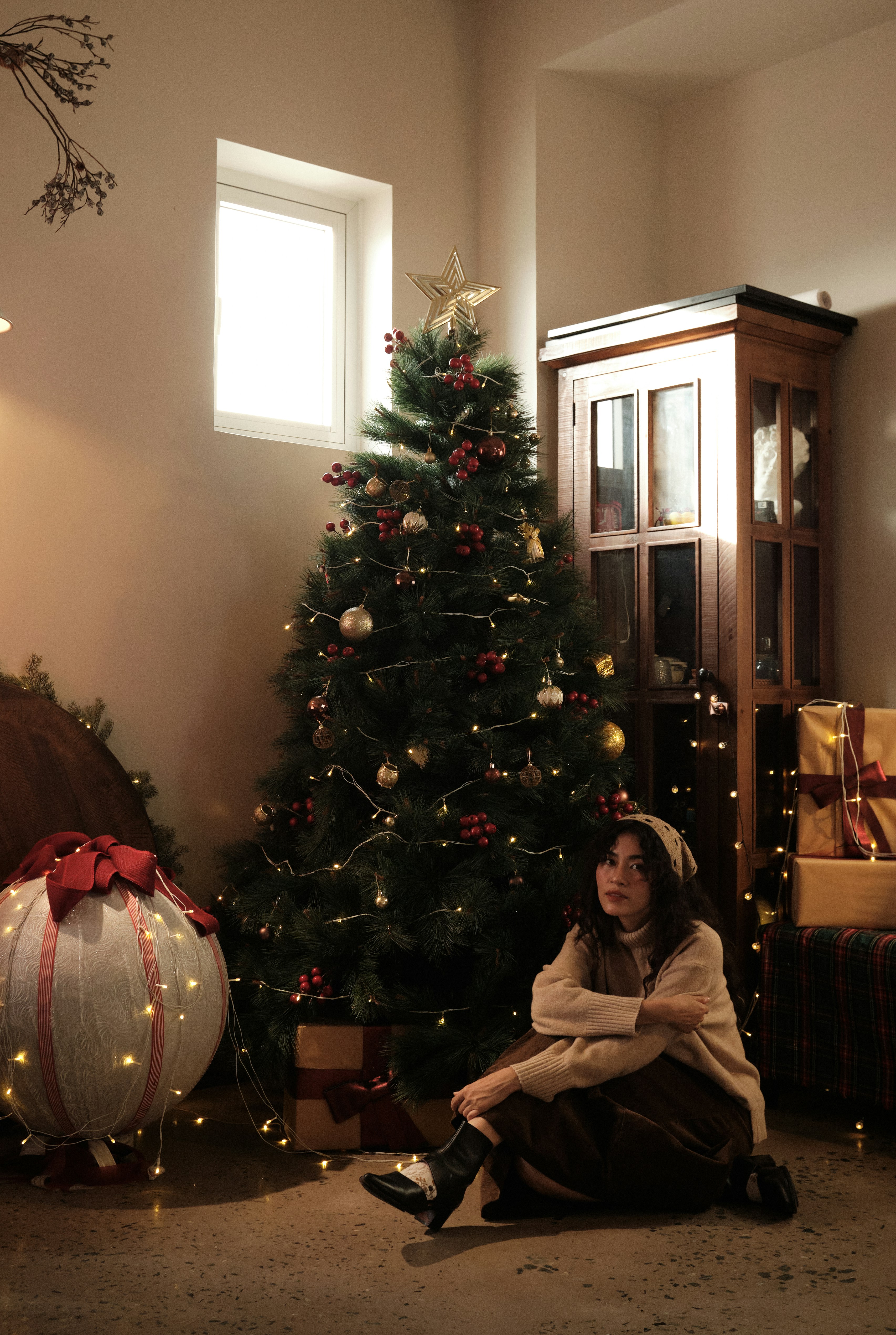 Woman sitting by a decorated christmas tree