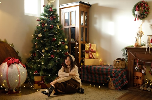 A girl sits by a decorated christmas tree and presents.